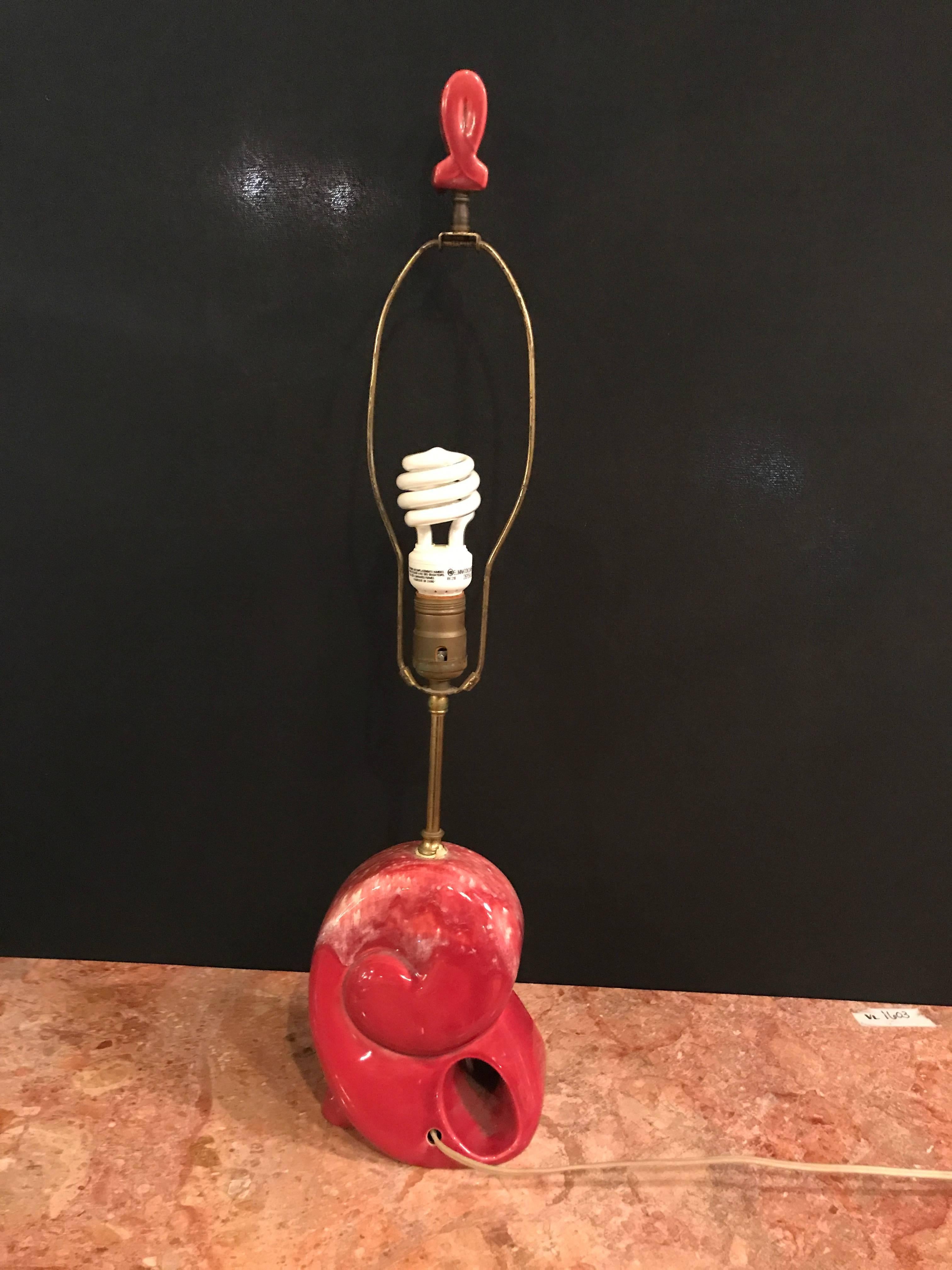 Pair of red Mid-Century Modern shell form table lamps. Primarily red and some white in color with drilled openings for the electrical cord these very fashionable table lamps would make a lovely statement in any room of your home. Both have matching