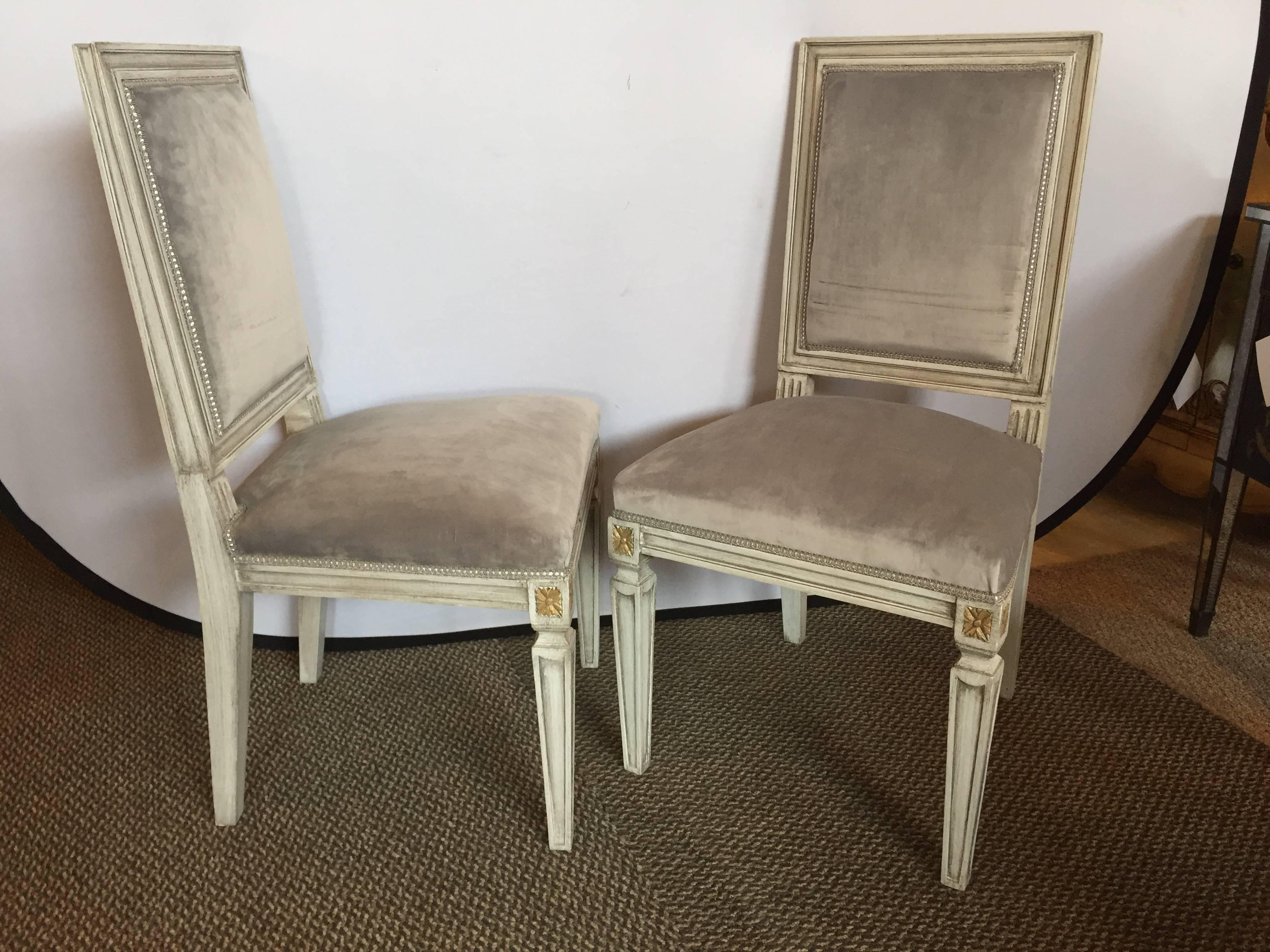 Parcel-gilt and paint decorated set of 12 Jansen style dining chairs in new suede upholstery. Can buy 6-8-10-12. The recessed tapering legs supporting an apron with carved corners and a padded seat and backrest both framed and decorated. This set a