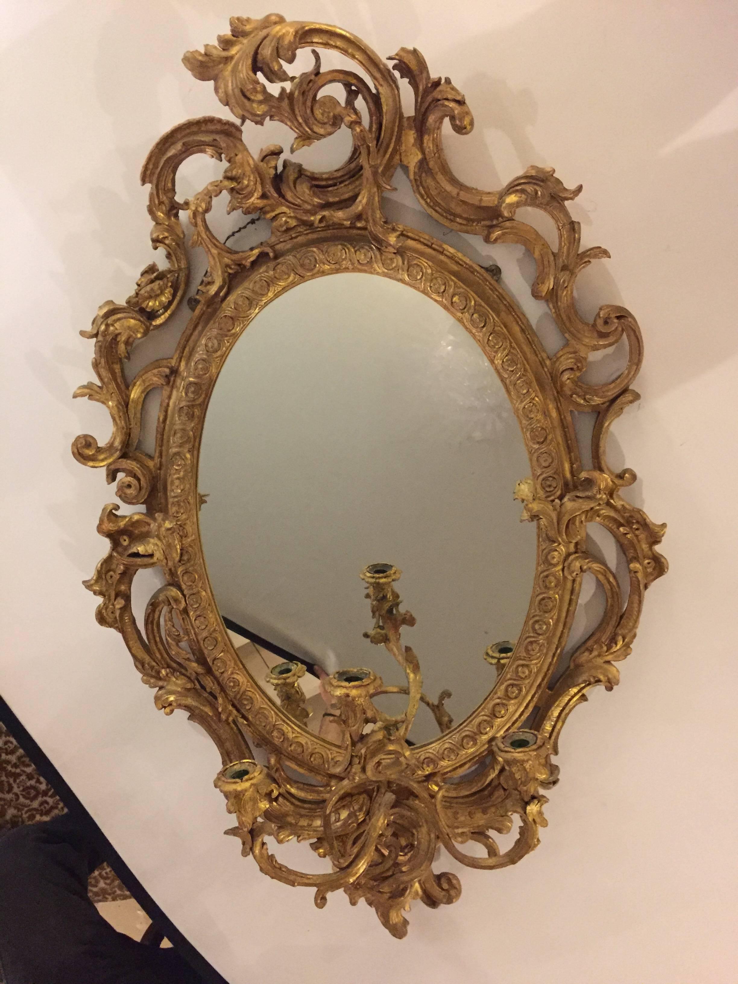 19th century pair of gilt and gesso wall mirror having three-arm sconce. This is a simply stunning pair of three-arm sconces with mirror backs and wonderfully carved wood and gesso frames. The centre oval mirror of clear and clean form having an