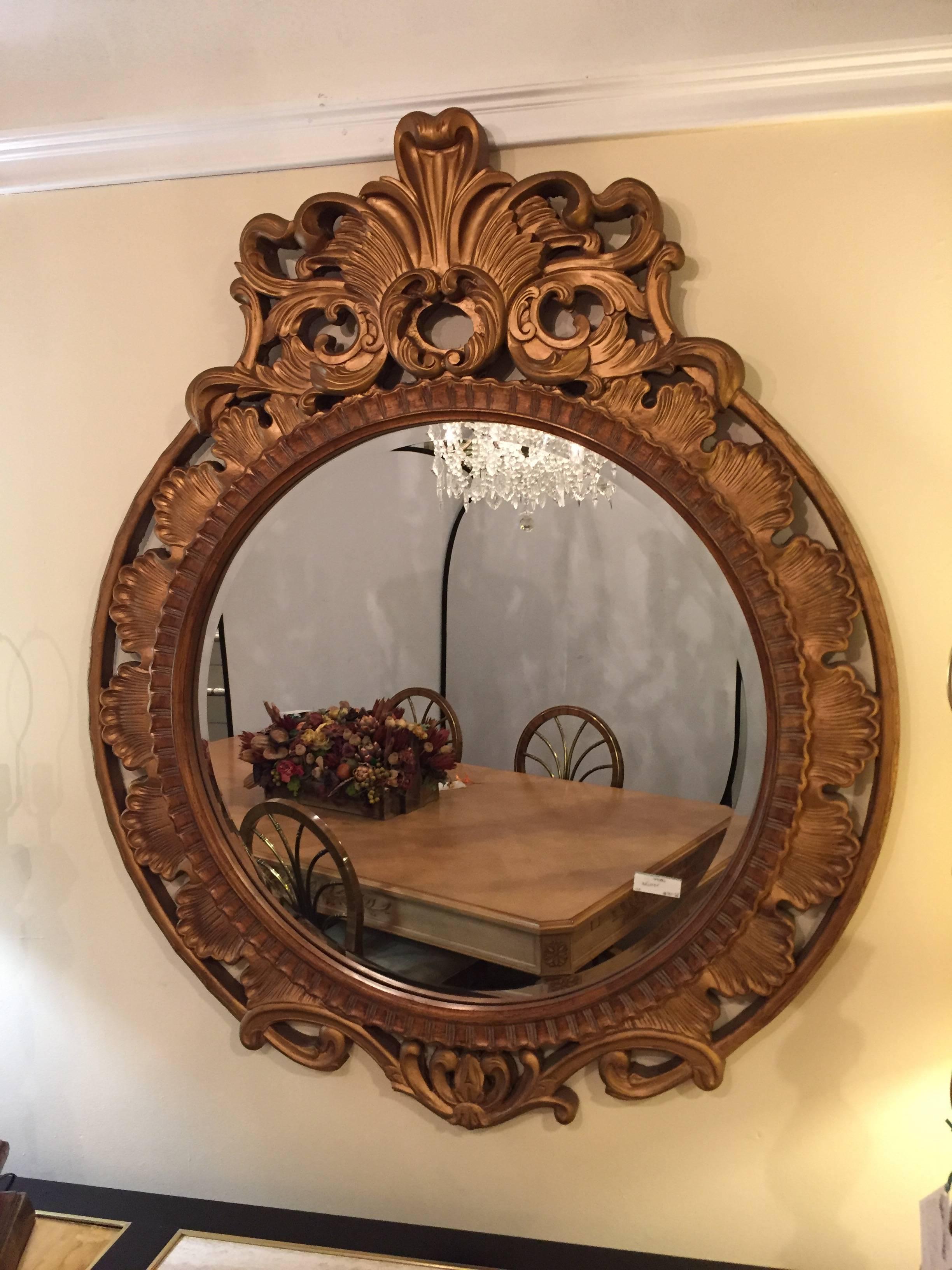 Palatial gilt decorated carved circular wall or console mirror. The clean and clear center circular mirror framed in a heavily carved giltwood frame. The interior frame of shell design flowing onto an outer frame of scroll and leaf design.