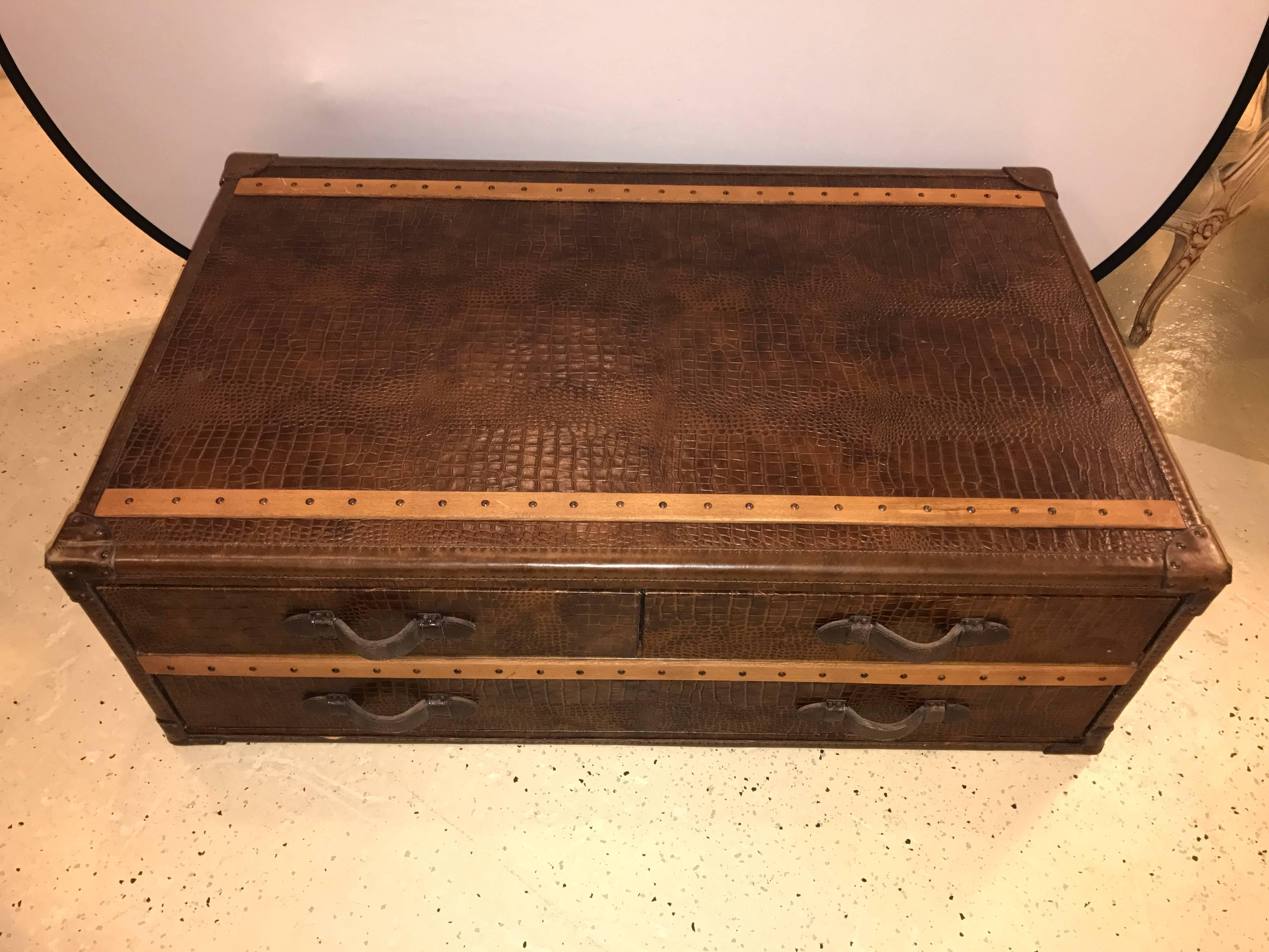 Leather alligator style oak trimmed trunk or coffee table. This fine coffee table has two upper drawers over one larger lower drawer all with leather strap pulls. The trunk itself with fine oak trim. Very sleek and stylish.
  