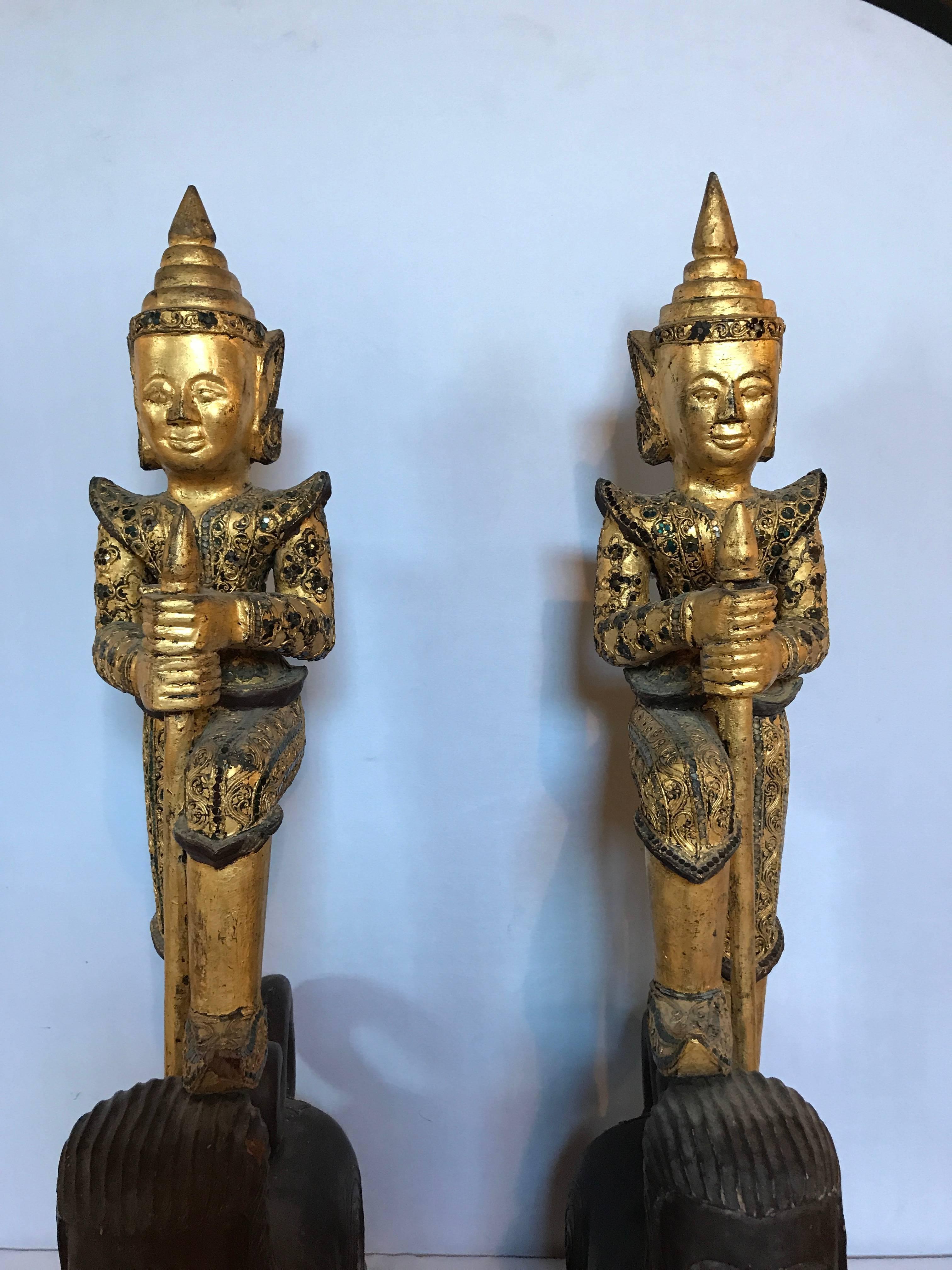 A pair of antique Thai figures. Each metal statue on a wooden carved base.