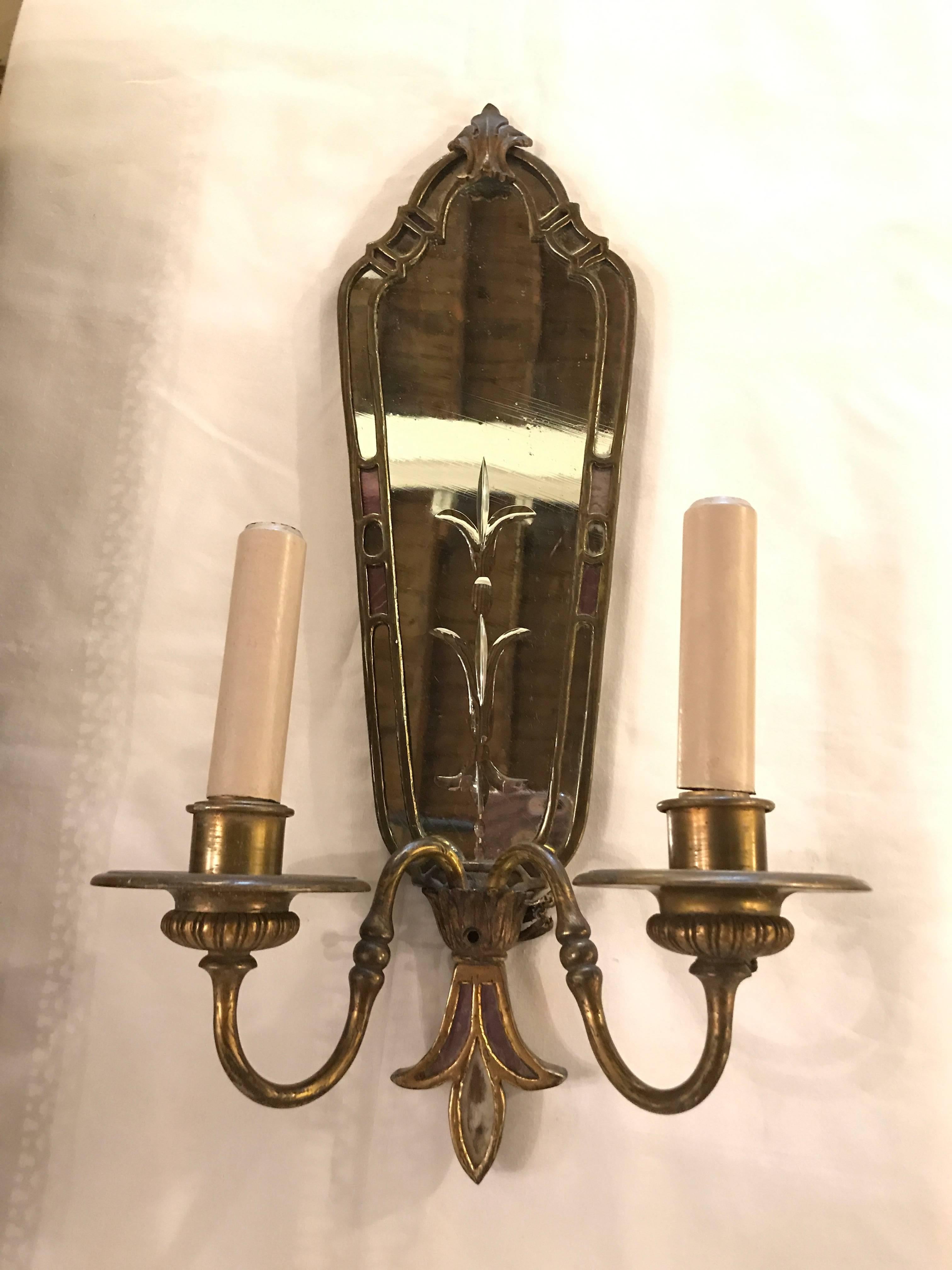 A pair of two-arm bronze antique mirrored back sconces each having an etched glass design of Fleur-de-lis. Very sleek and fine.