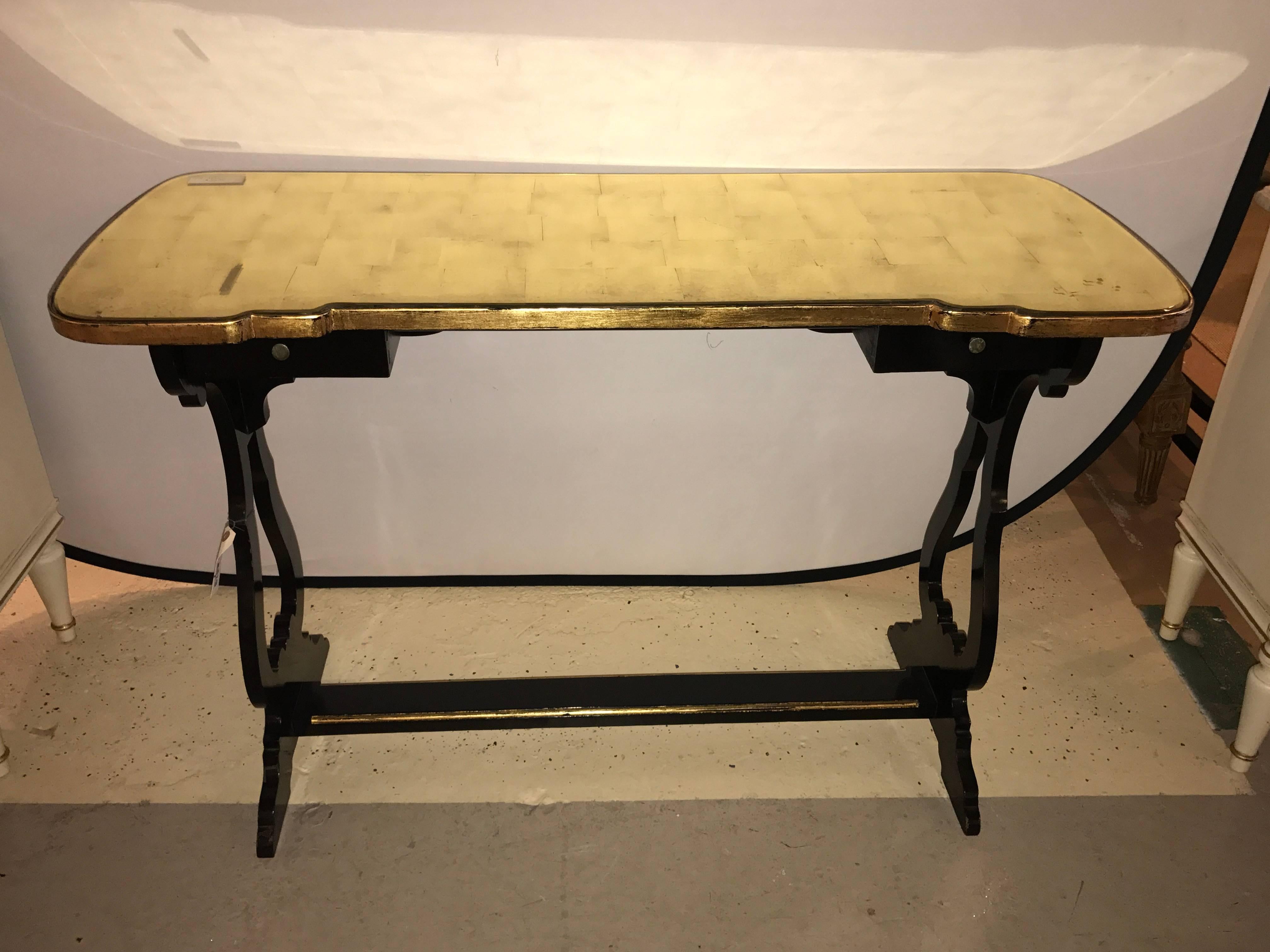 French ebonized console table or desk with gilt glass top Jansen style. Bringing Hollywood Regency to the forefront comes this finely ebonized desk in the fashion of the iconic Maison Jansen. The ebonized and gilt gold base having a lower shelf with