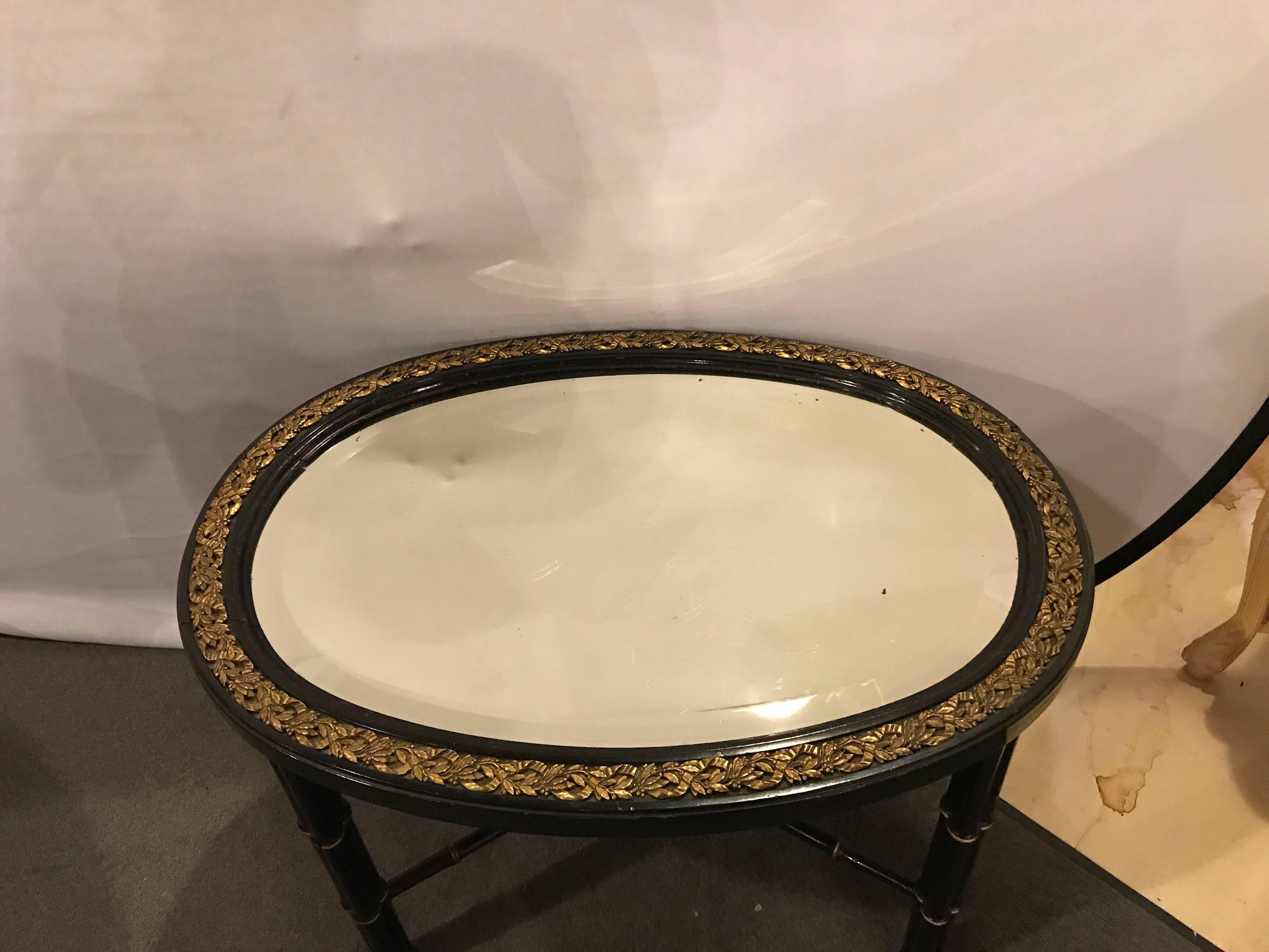 Schwarzer ovaler Hollywood Regency Couchtisch mit abgeschrägter Spiegelplatte und Bronzebeschlägen im Angebot 1