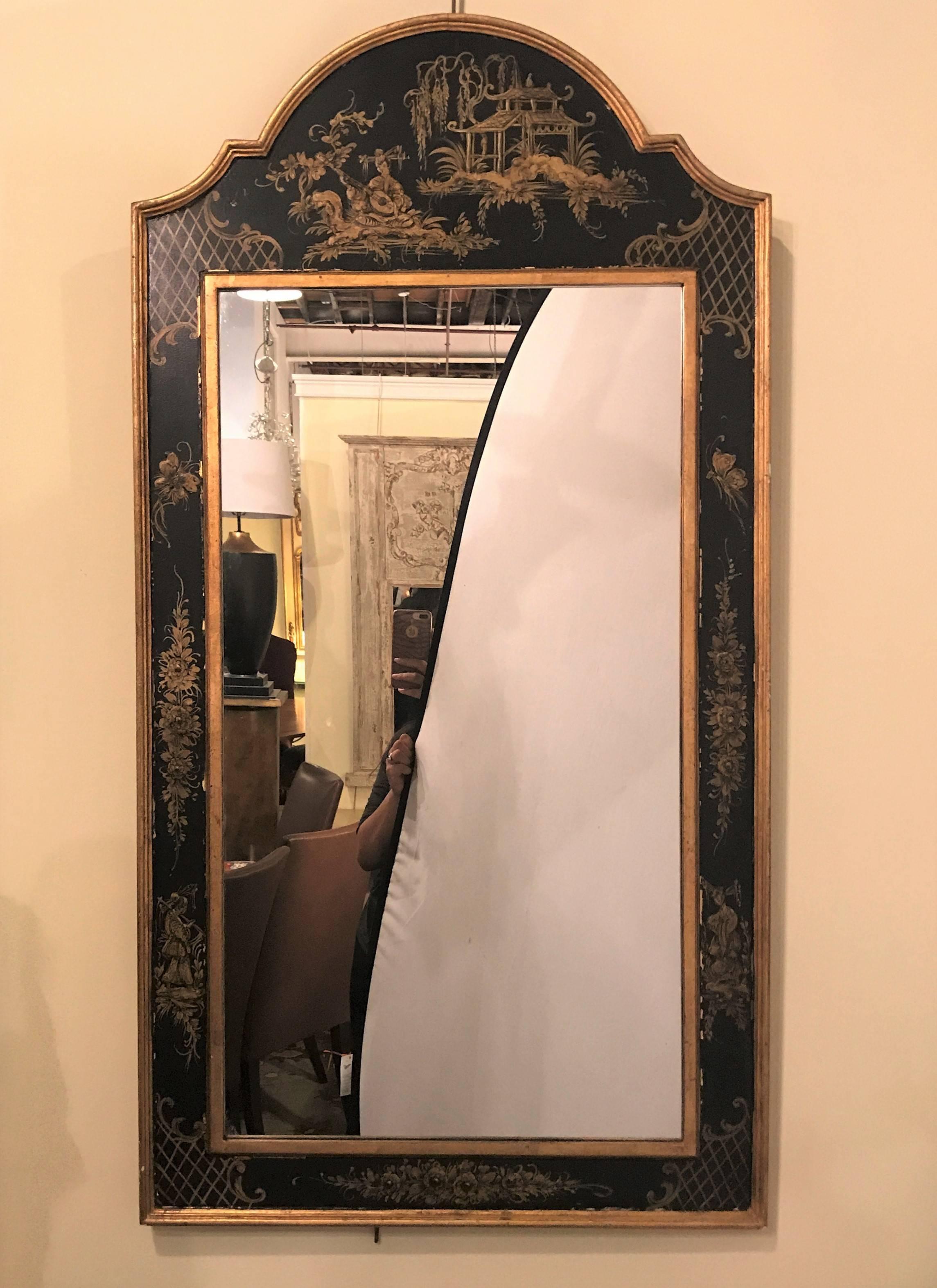 A chinoiserie ebony and gilt decorated wall or console mirror. The clean center mirror panel framed in a paint decorated ebony and gilt frame depicting a woman playing a musical instrument with a pagoda in the background. The frame itself with