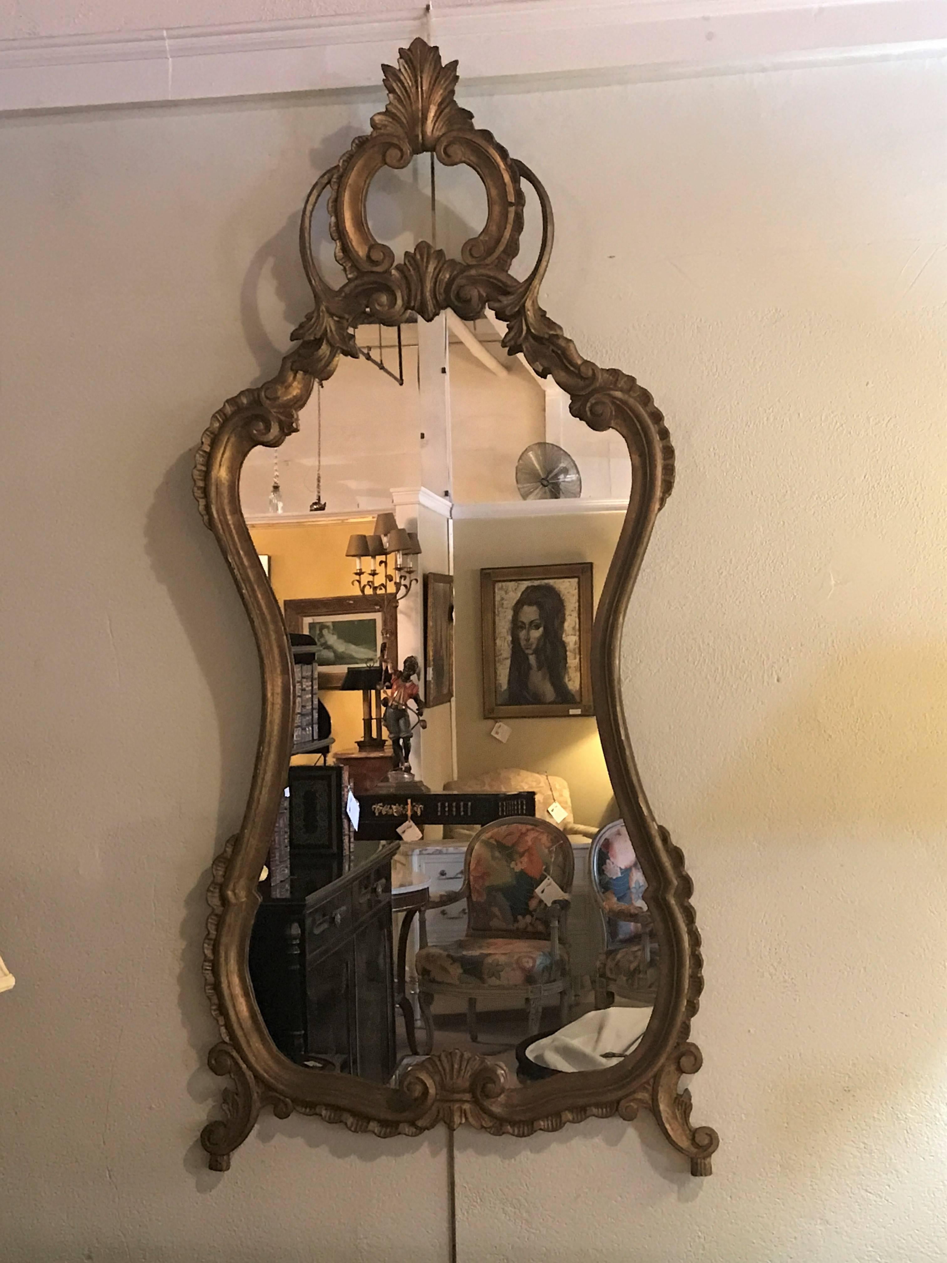 A nice pair of Italian Rococo style wall or console mirrors. The clean center mirror panels having finely carved gilt gold frames of scroll and leaf design both sitting on footed bases.
