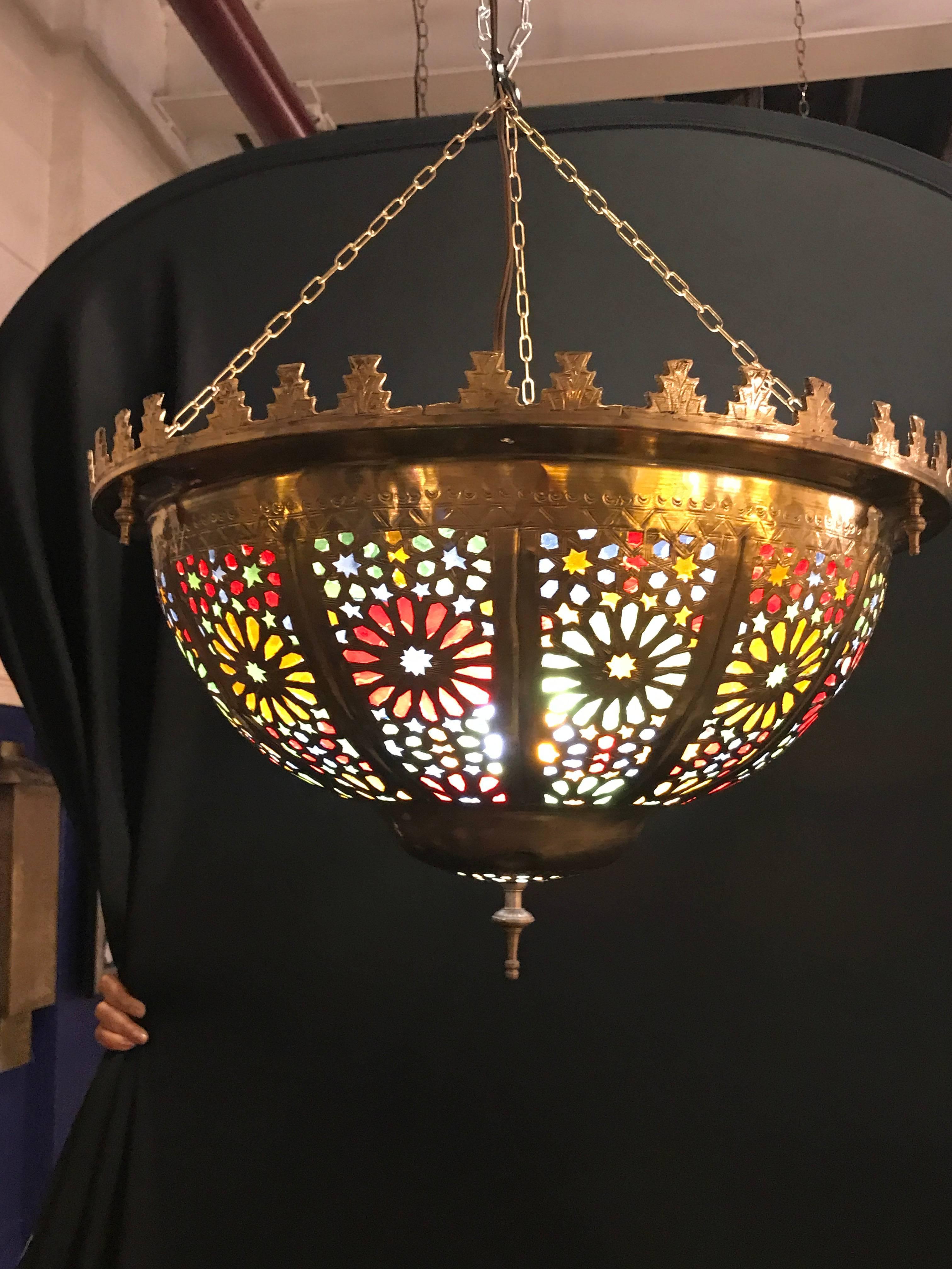 This captivating and elegant golden-colored round-shaped lamp has been created in a Moorish style and features individually wrought multicolored glass panes and elaborate hand tooled design work. Adds exotic distinction to any living space. Actual