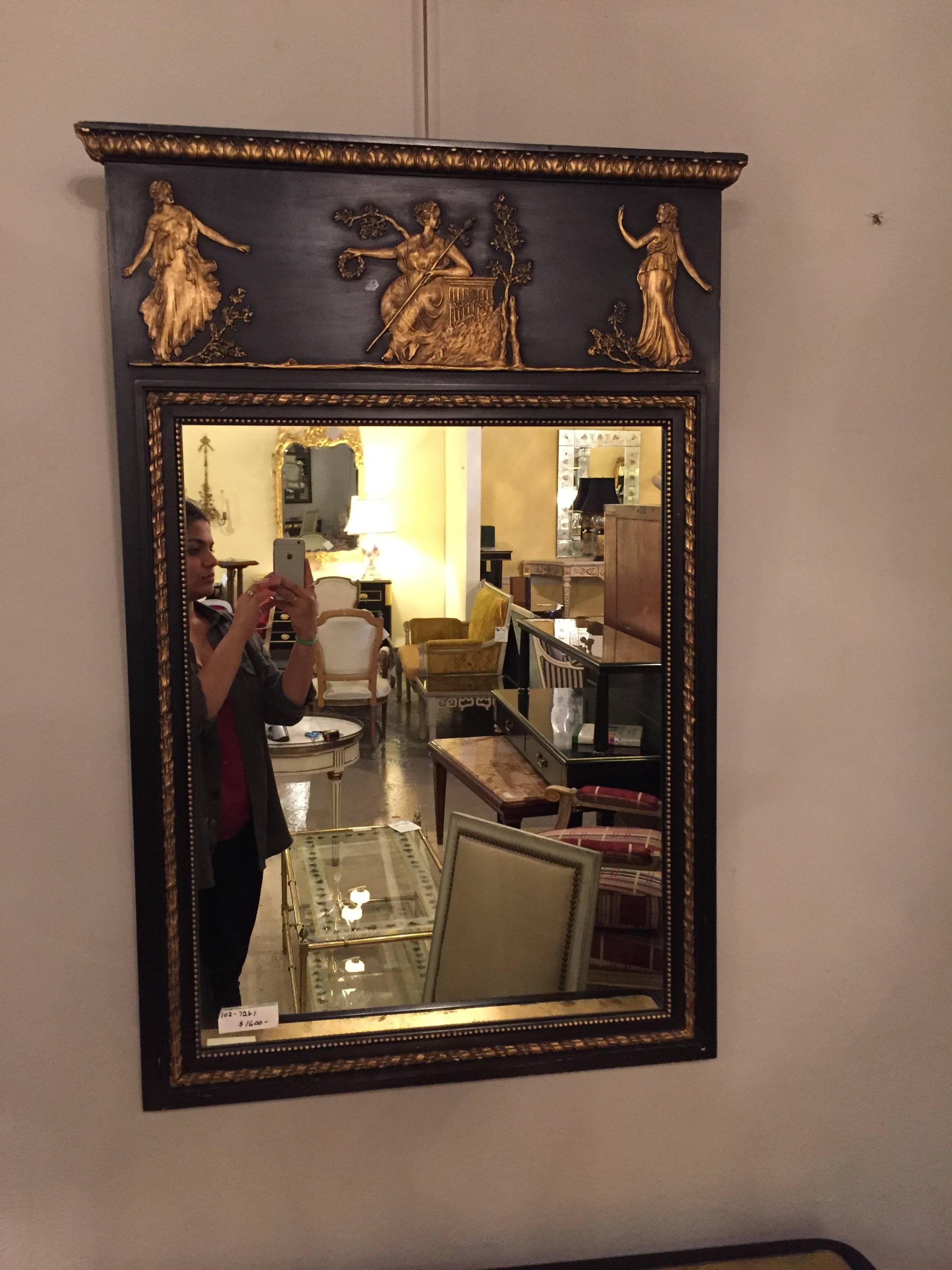 Ebonized neoclassical mirror by Friedman Brothers depicting dancing and musical playing maidens. The center beveled mirror in a finely carved ebony and gilt decorated frame.