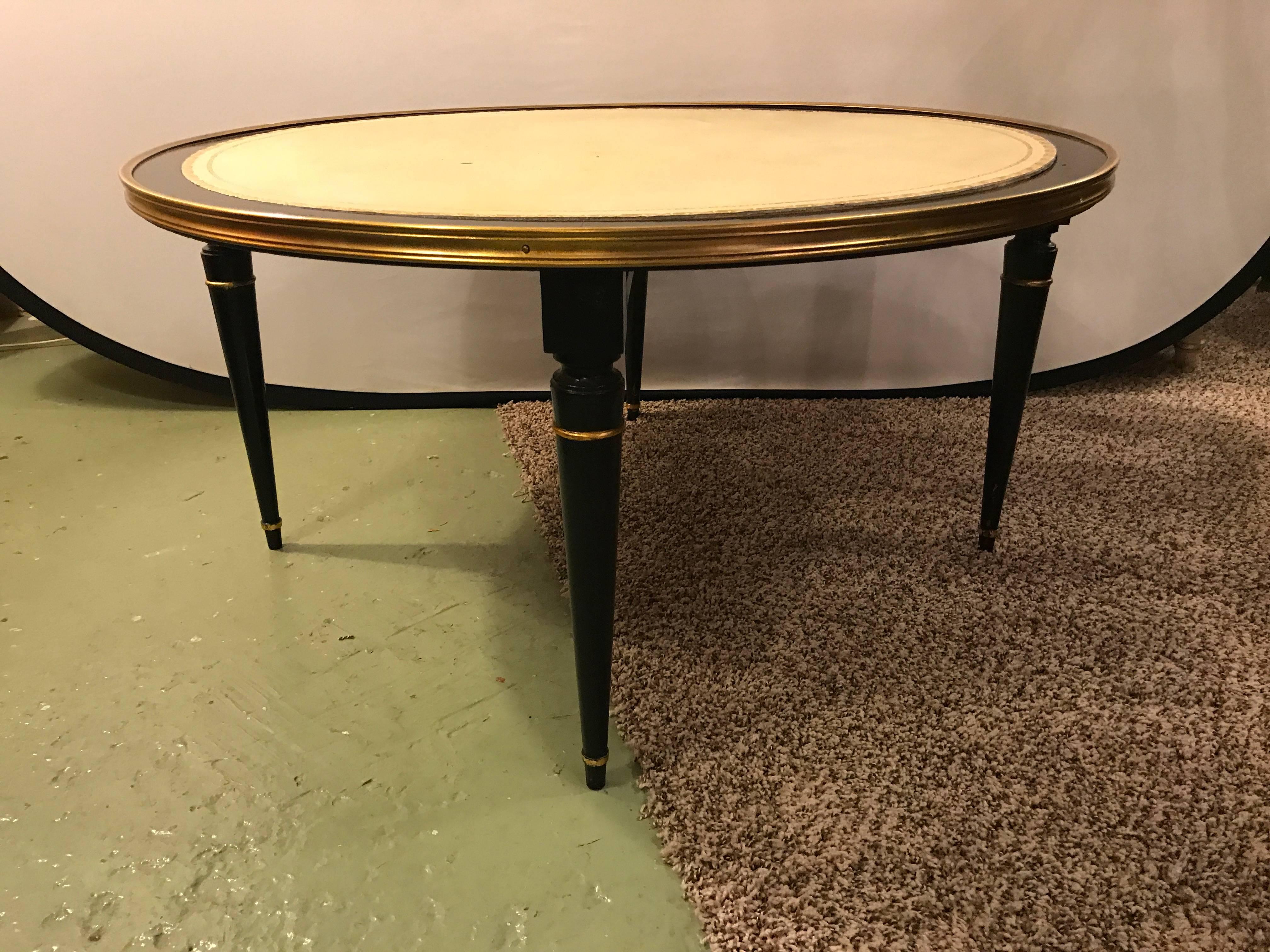 An ebonized Hollywood Regency coffee or low table with leather top. The circular leather top having an ebony border sitting on Louis XVI styled legs in an ebony and gilt decorated finish.