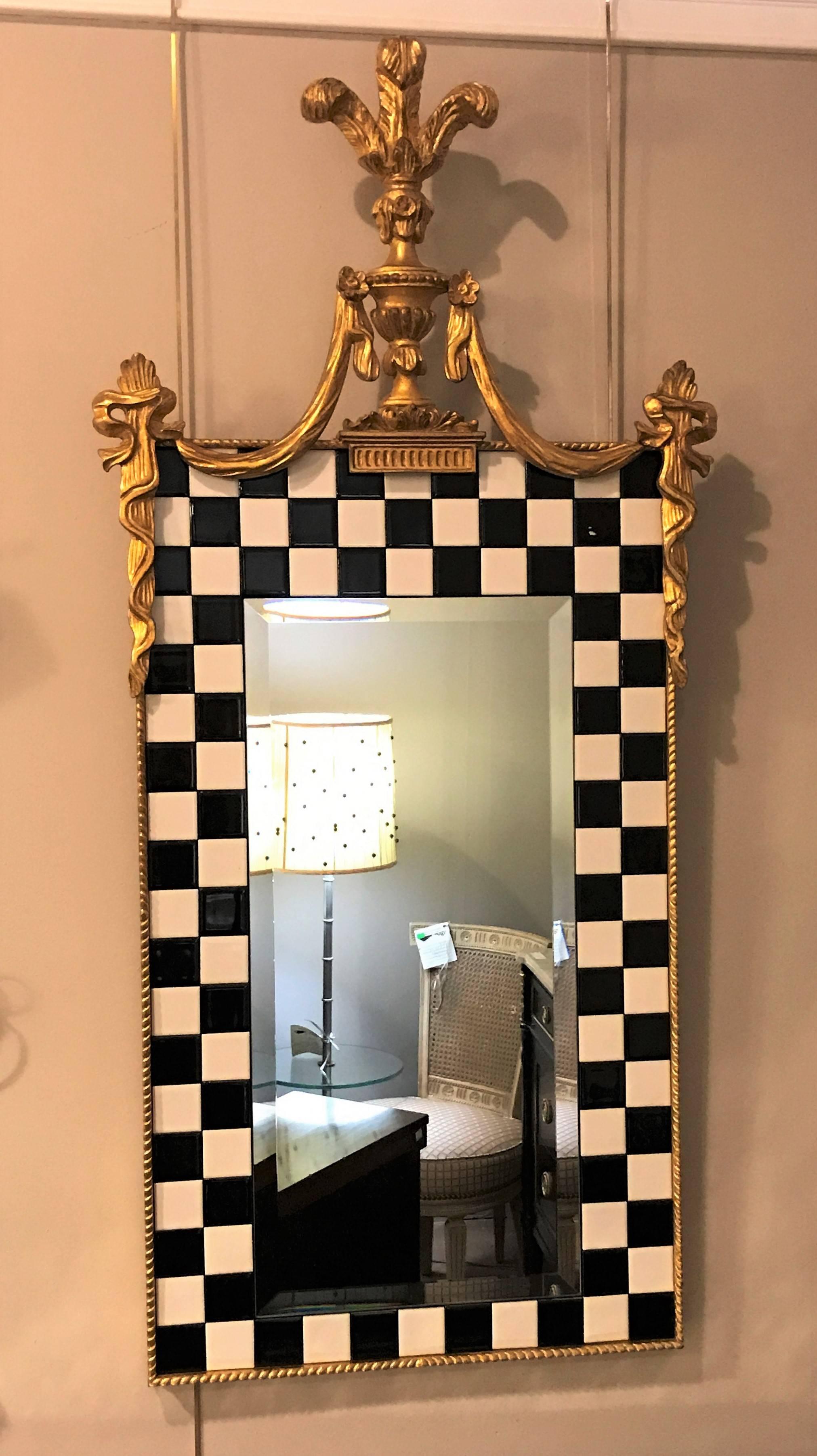 A carvers guild company gilt gold and checker board decorated mirror. This Hollywood Regency style gilt wall or console mirror is finely decorated with a rope carved border outside of the checkerboard porcelain decorated frame. The beveled centre