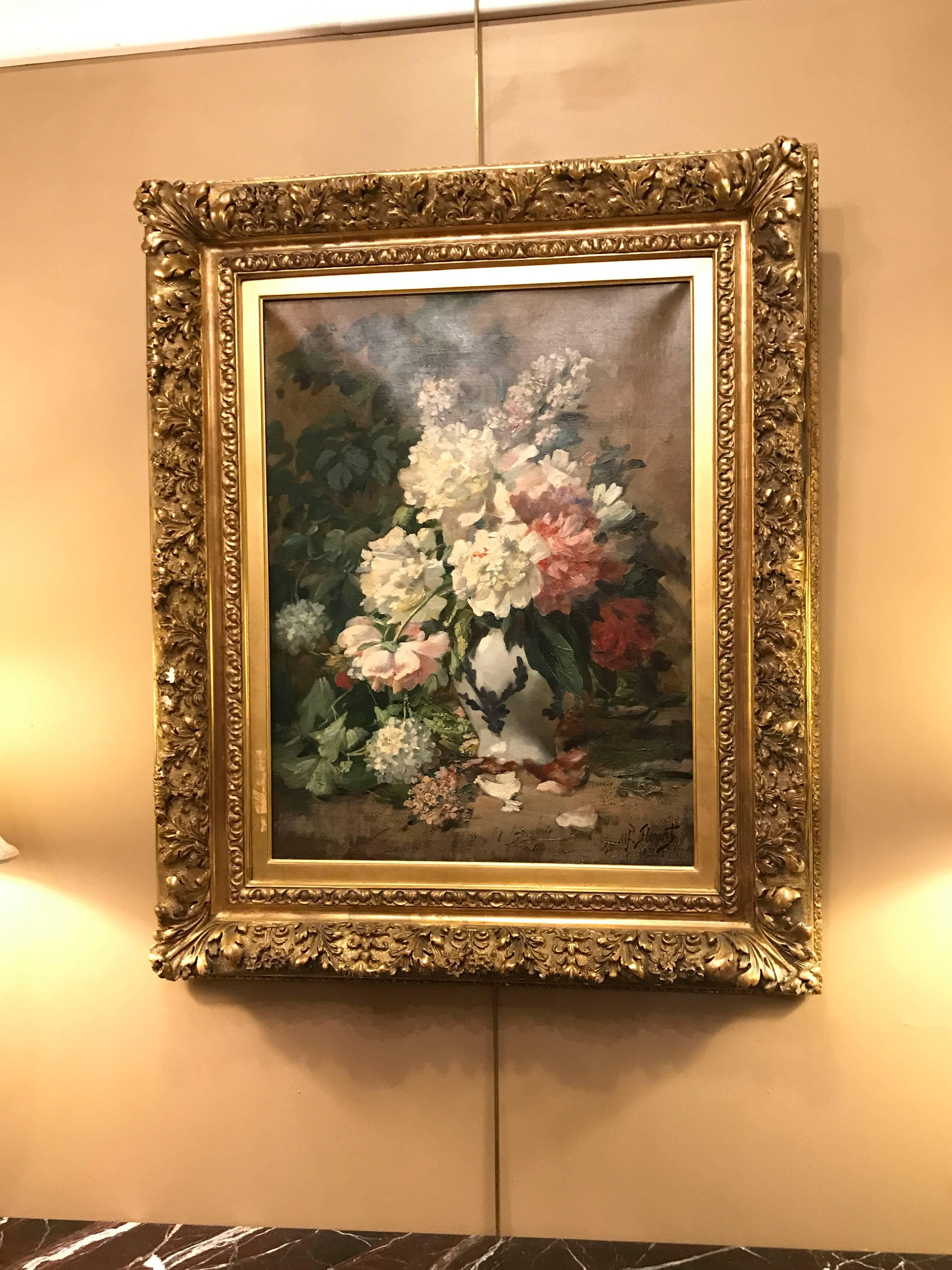 19th century French oil on canvas of a still-life of flowers in a white vase signed. This finely painted oil on canvas was done in the late 1800s and sits in a finely carved wood and gesso frame of floral design. The oil painting itself simply a