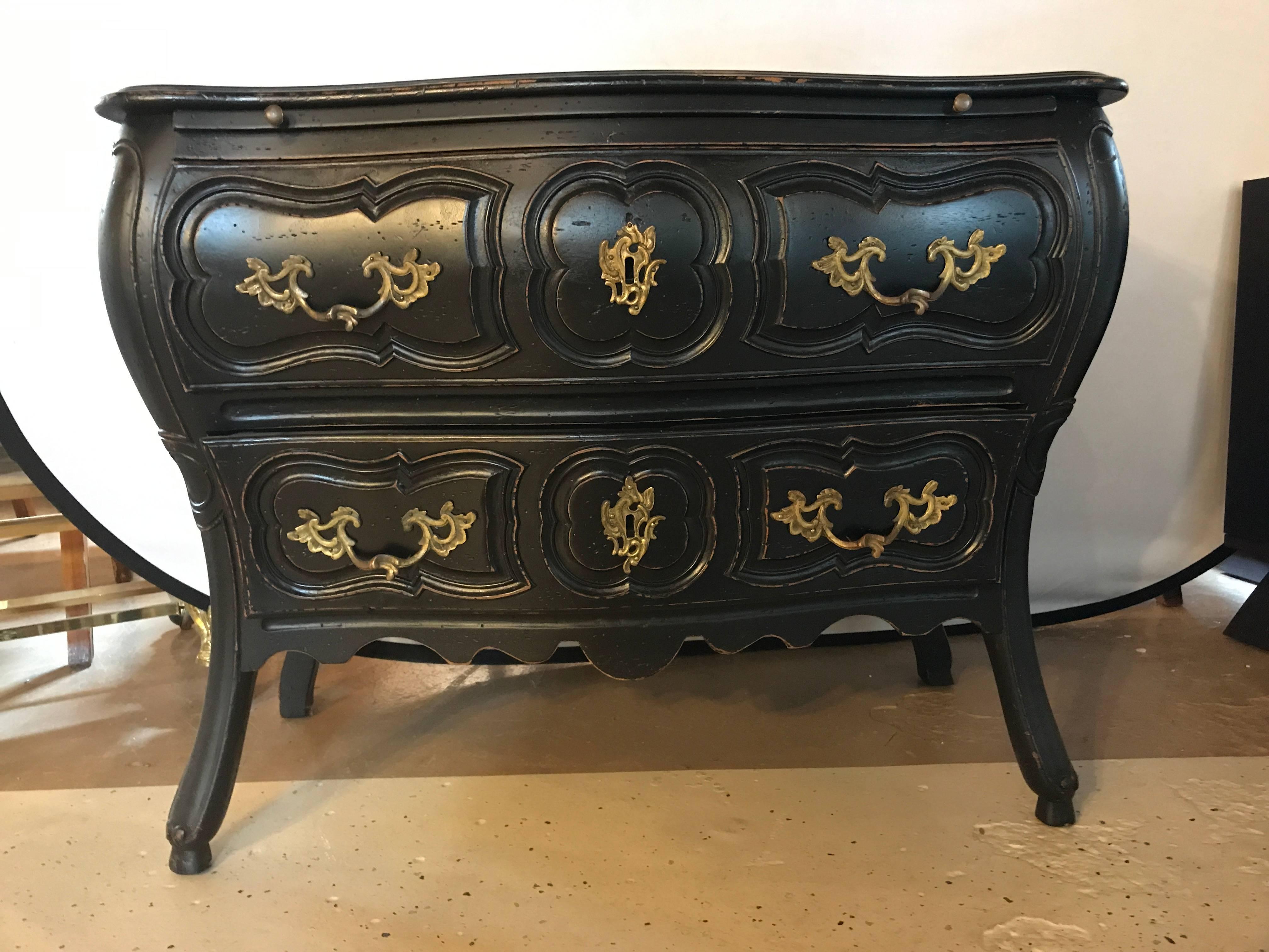 Black distressed bombe commode or nightstand with bronze mounts and pull-out tray top. In this Louis XV style having a Hollywood Regency Flair stands this custom oak secondary small chest or bedside stand with a pull-out writing or eating tray.