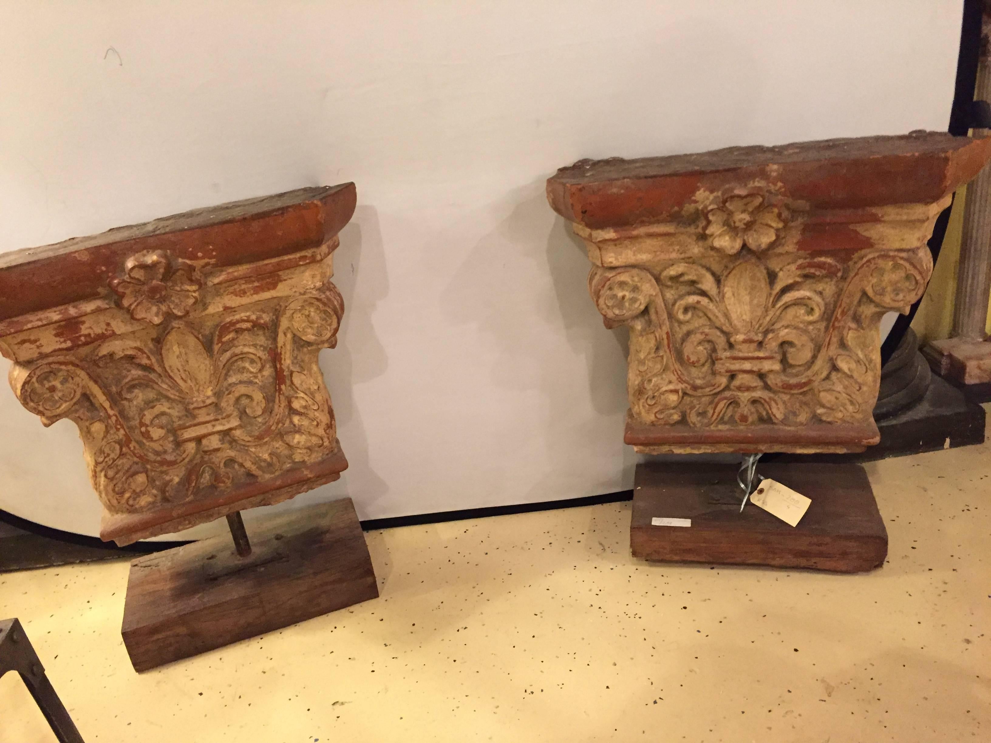A pair of antique architectural stone building tiles mounted on stands. Each solid wooden pedestal used to mount this ancient fleur-de-lis decorated building tile. The pair can easily form a garden bench or console table as is needed.
