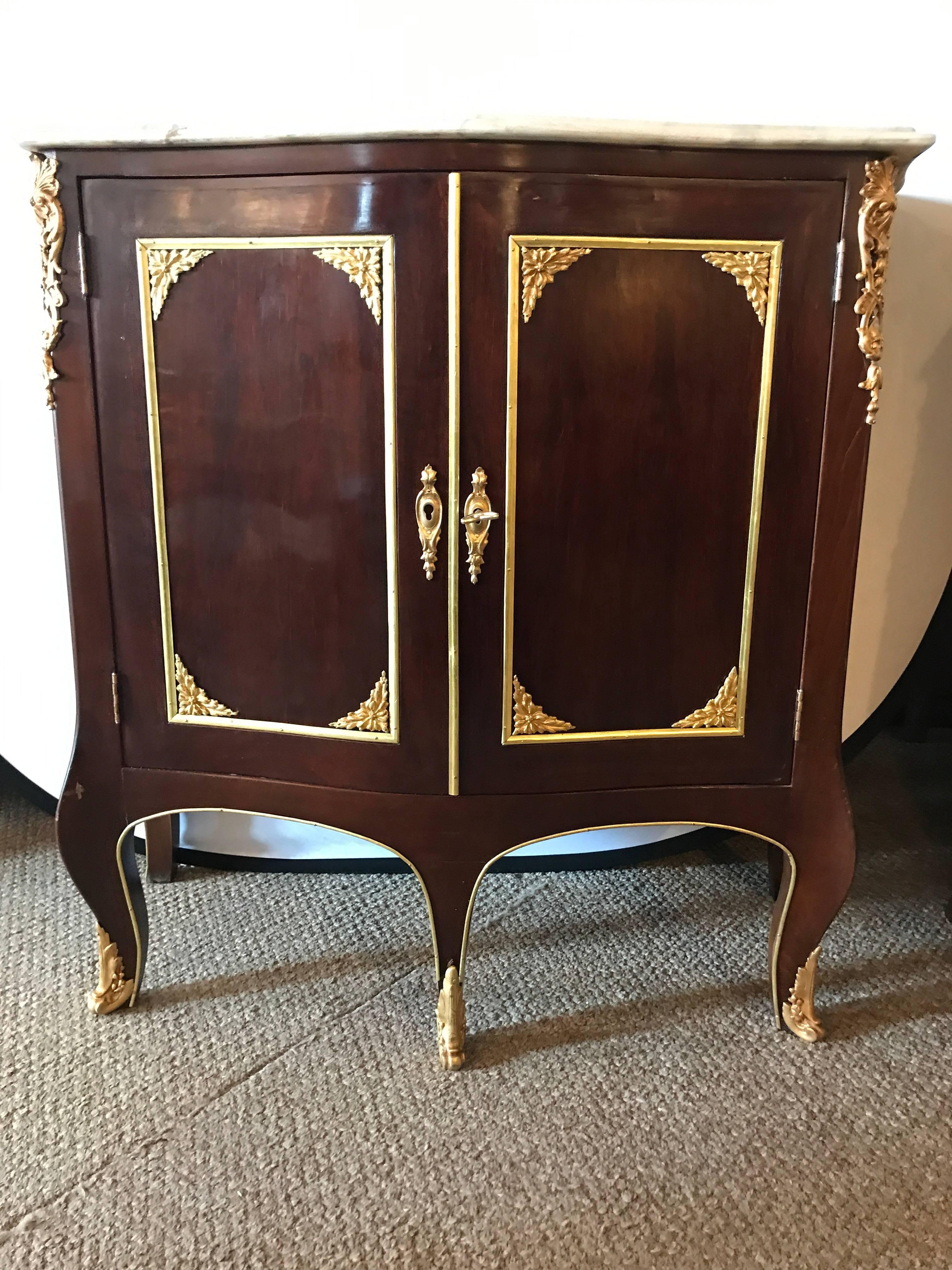 Pair of Jansen style oak interior two-door marble-top bedside cabinets or end tables which can easily be used as console tables. This finely constructed pair of end table or console tables have all over bronze mounts and are fashioned in the Louis