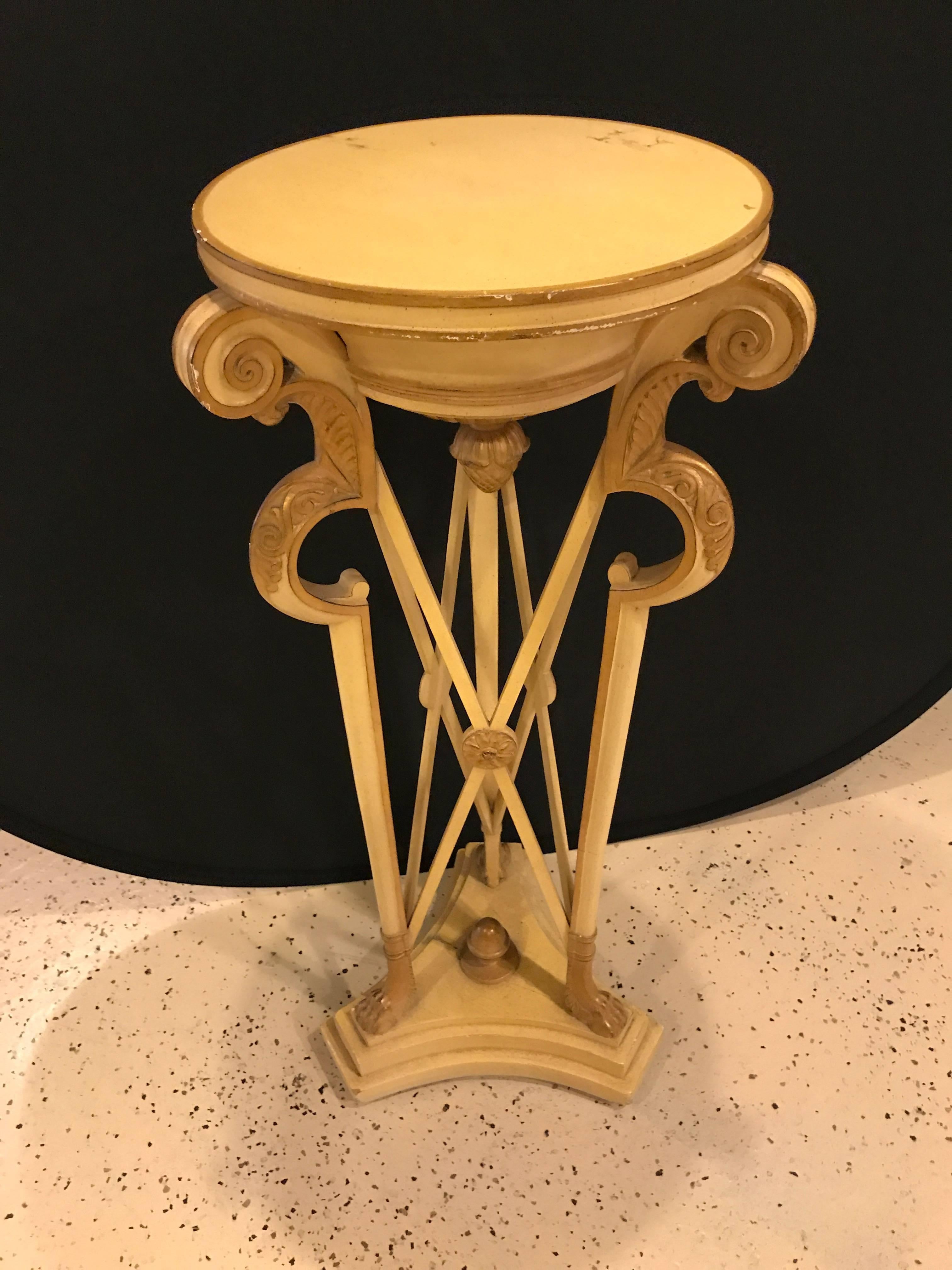 Hollywood Regency style carved ivory color and gilt decorated pedestal. Standing on a pedestal base with gilt claw feet supporting an X-formed column with gilt hi lights comes this finely crafted pedestal stand.