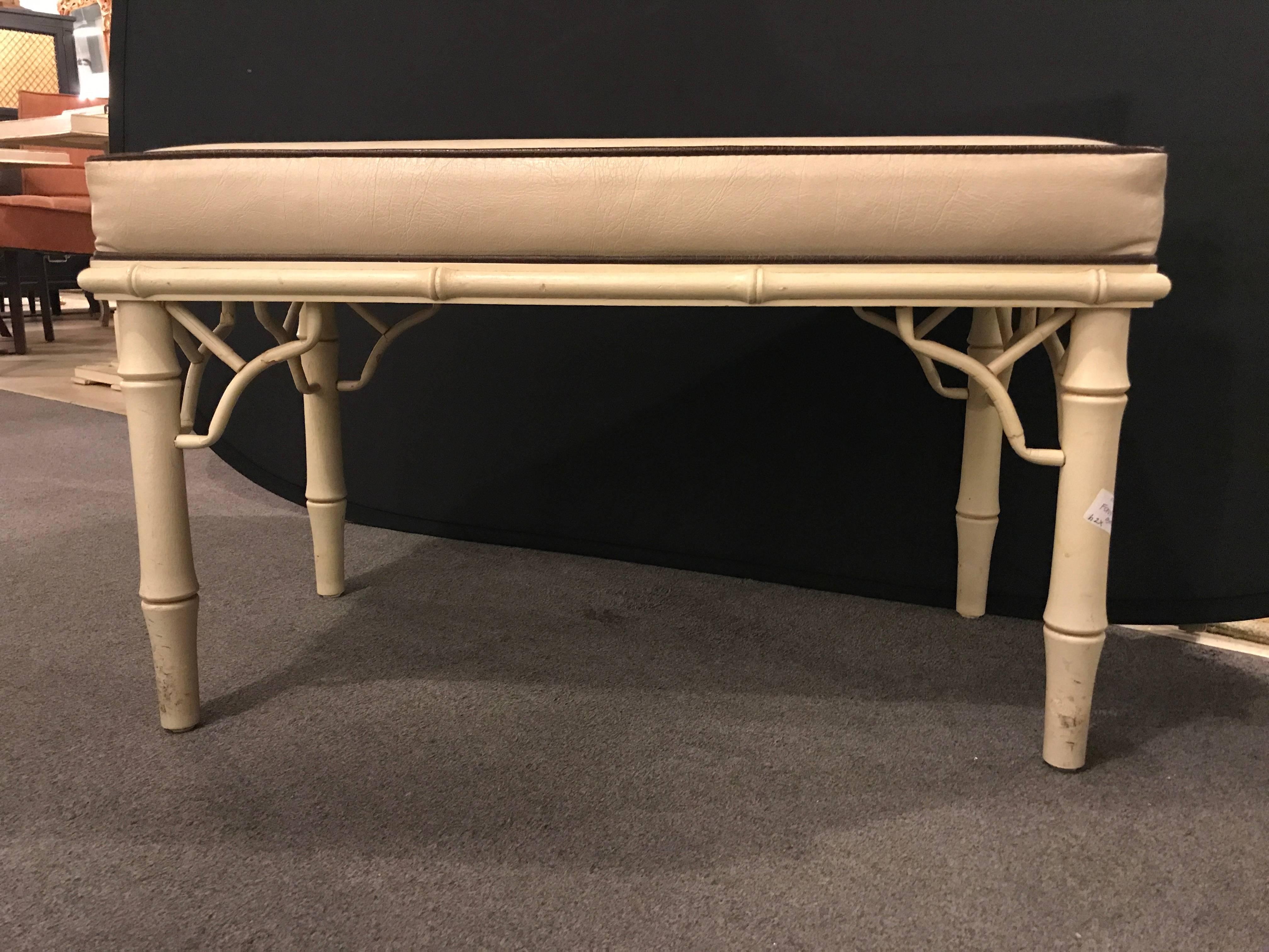 A pair of faux bamboo benches each in a cream and brown border faux leather.