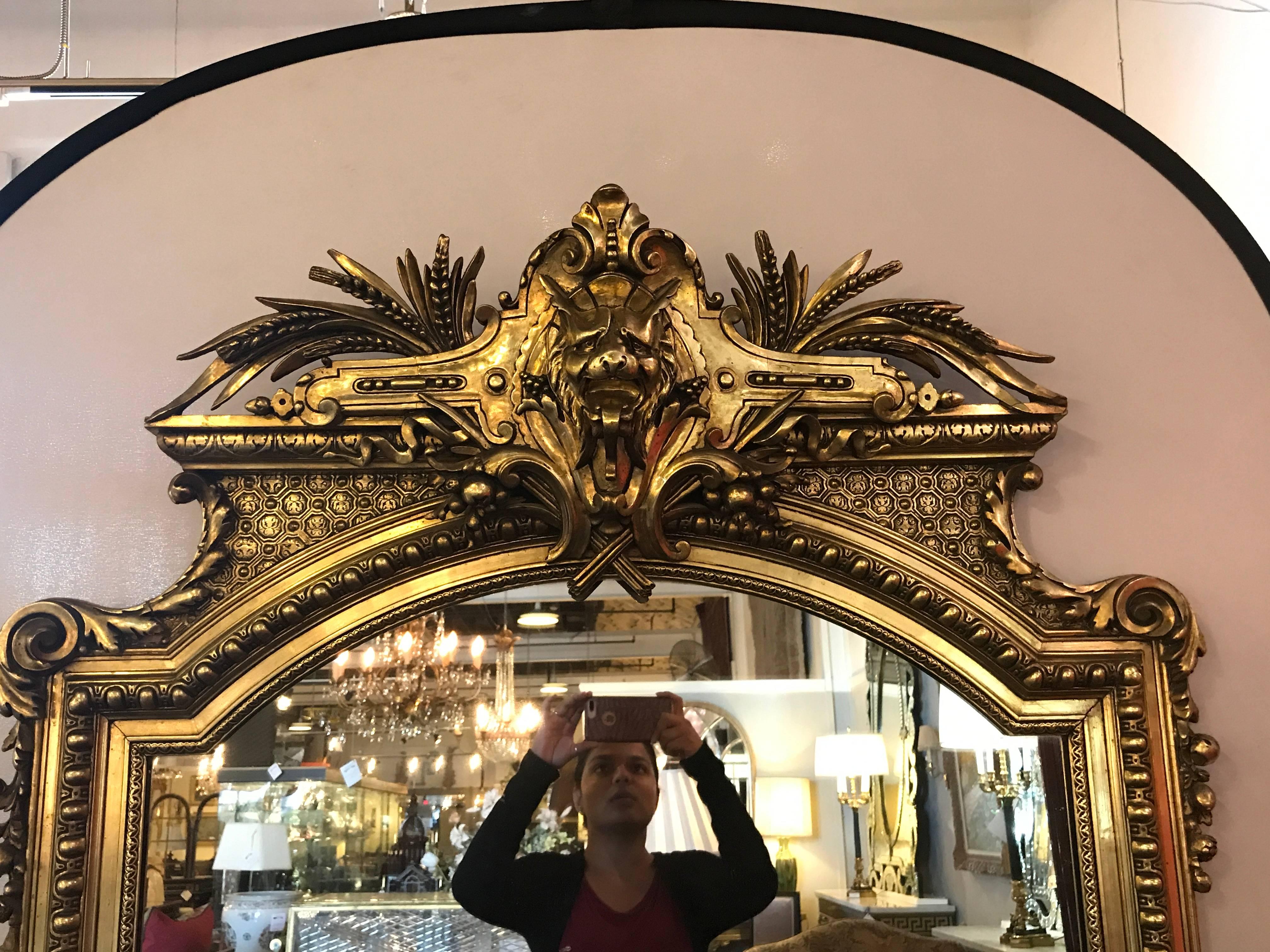 19th century console or pier mirror with carved lion form crest. This mirror with possibly the finest gilt gold I have ever seen. The center panel in a gilt frame of rectangular form with button framing. The whole terminating in a finely carved loin