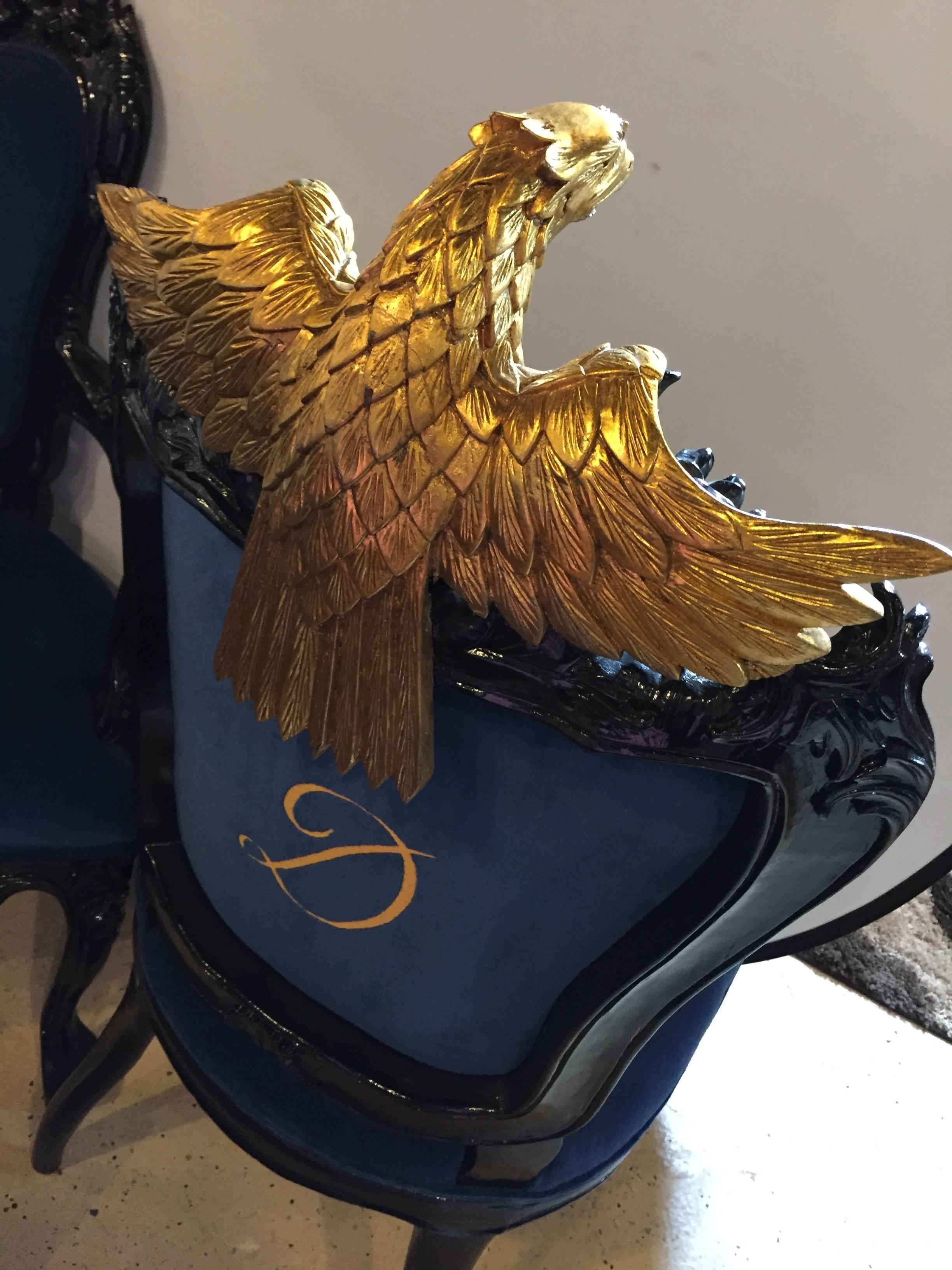 Set of eight, pair of arm and six side, Versace style ebony dining room chairs each having a carved winged eagle in flight. These heavily carved black lacquered dining chairs depict the Hollywood Regency flair and glamour era at its peak. The carved