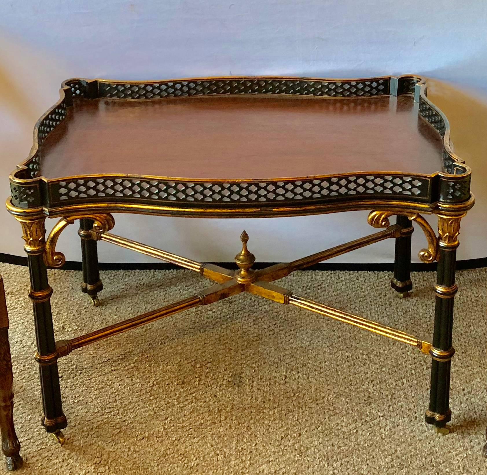 A Ralph Lauren Brook Street cocktail or coffee table. This ebony and giltwood decorated coffee or low table having a pierced gallery and X form undercarriage define the Hollywood Regency Era. The top is a fitted tray that can be removed and used to