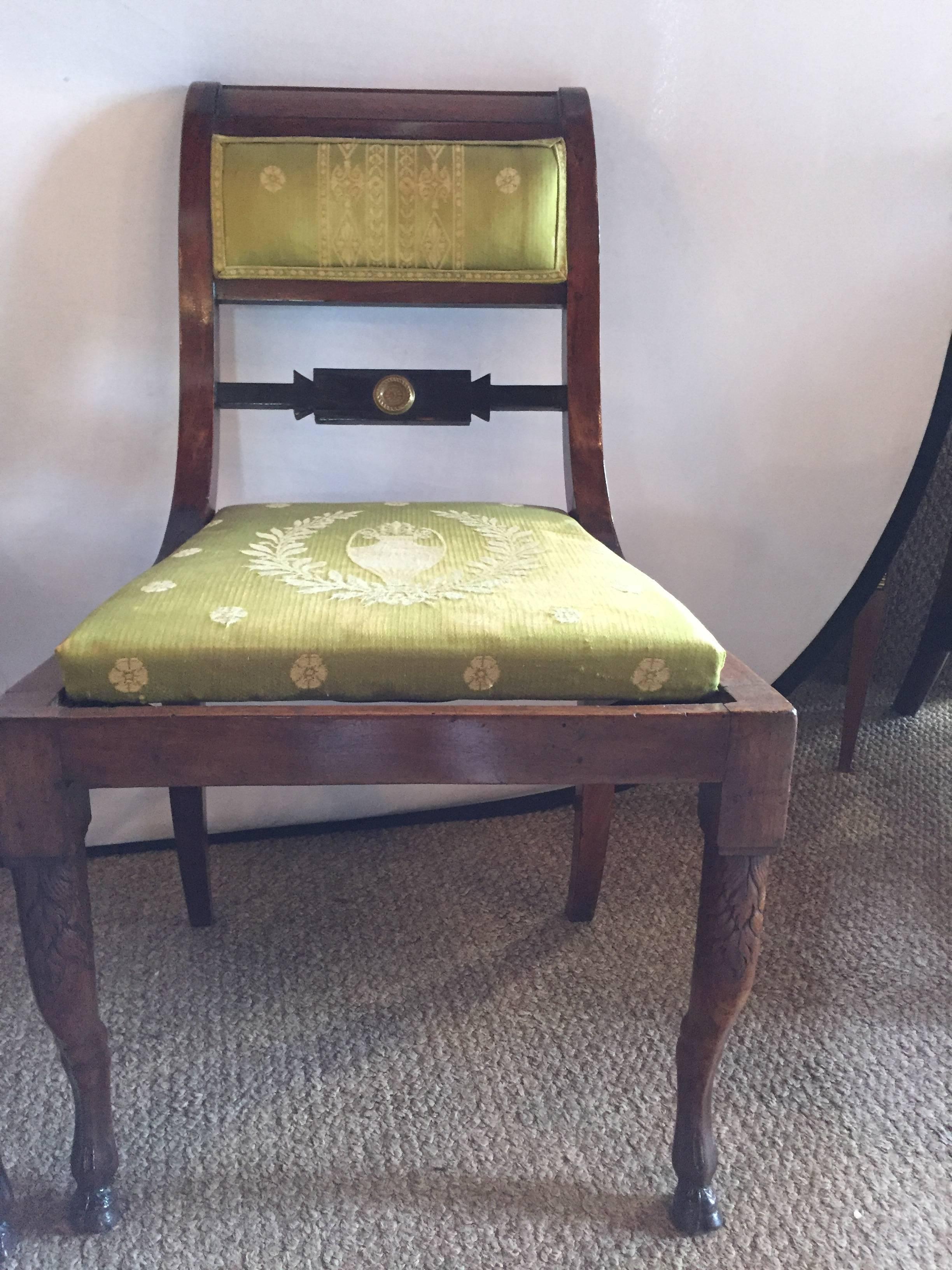 A pair of early 19th century antique Regency period chairs. This fine pair of mahogany side chairs each having hoof feet and embroidered silk seat and backrests define the era at its finest point in time.