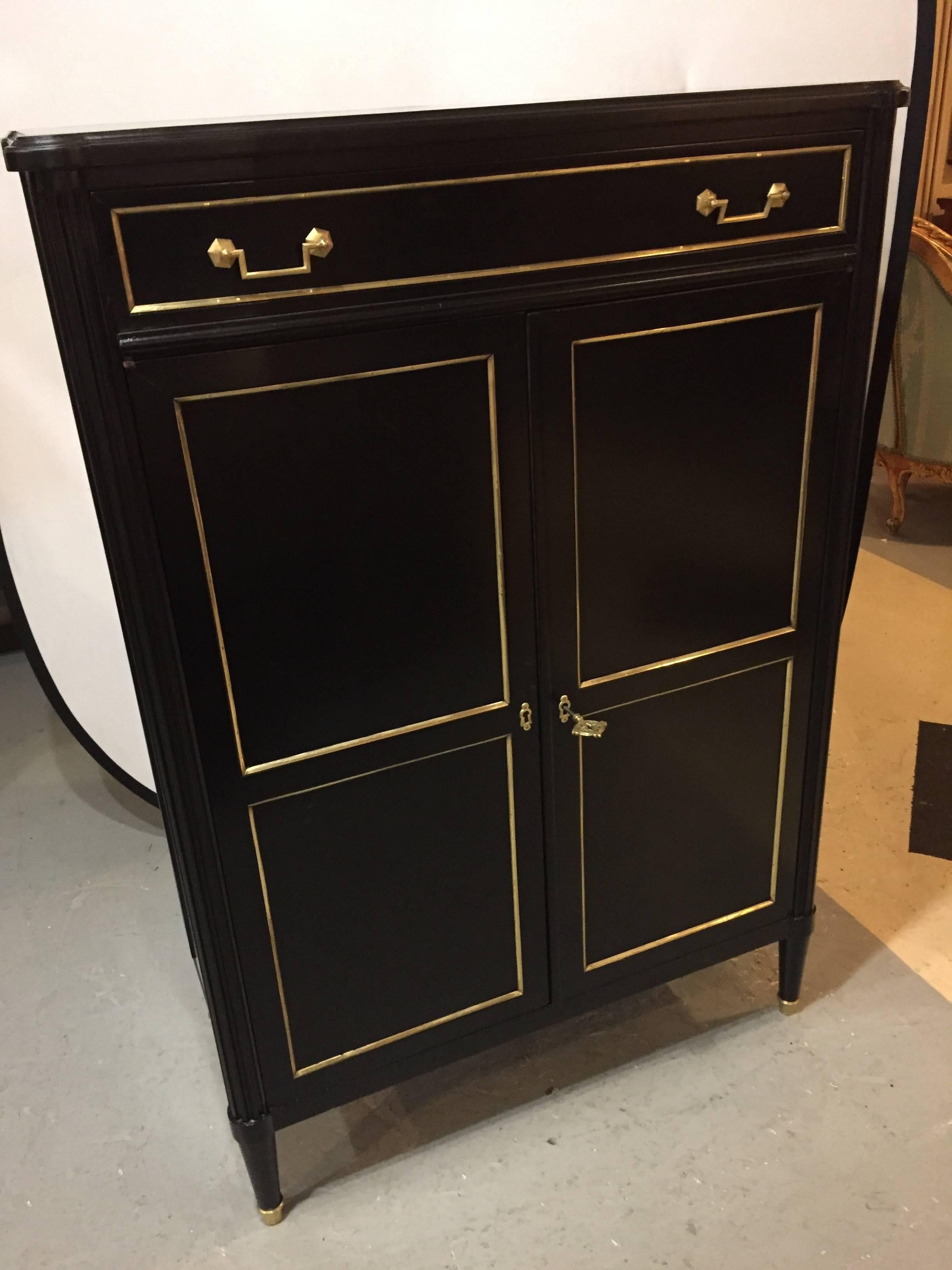 A Maison Jansen style ebonized Hi chest. Having a pair of bronze framed doors leading to a group of interior drawers this Louis XVI Hollywood Regency inspired chest of drawers is in fine condition having been recently refinished. With a top drawer