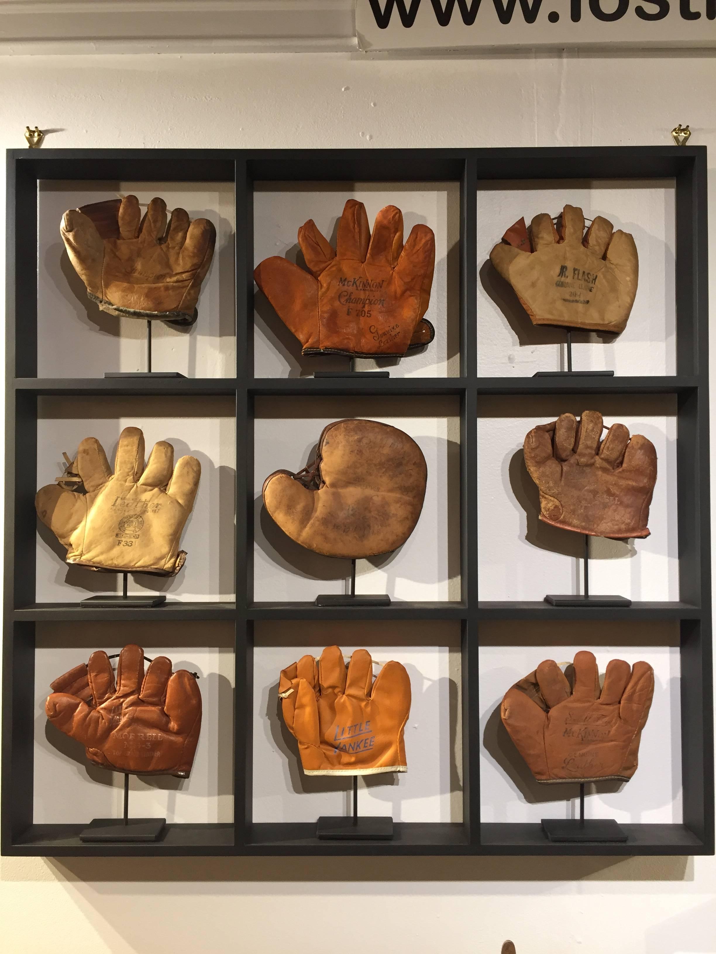 Rare antique miniature children's set of nine custom framed baseball gloves or mitts in a custom frame by this highly sort after designer. Each vintage mitt on an iron hand made stand sitting in its on space on a nine shelf wooden wall shelf. Custom