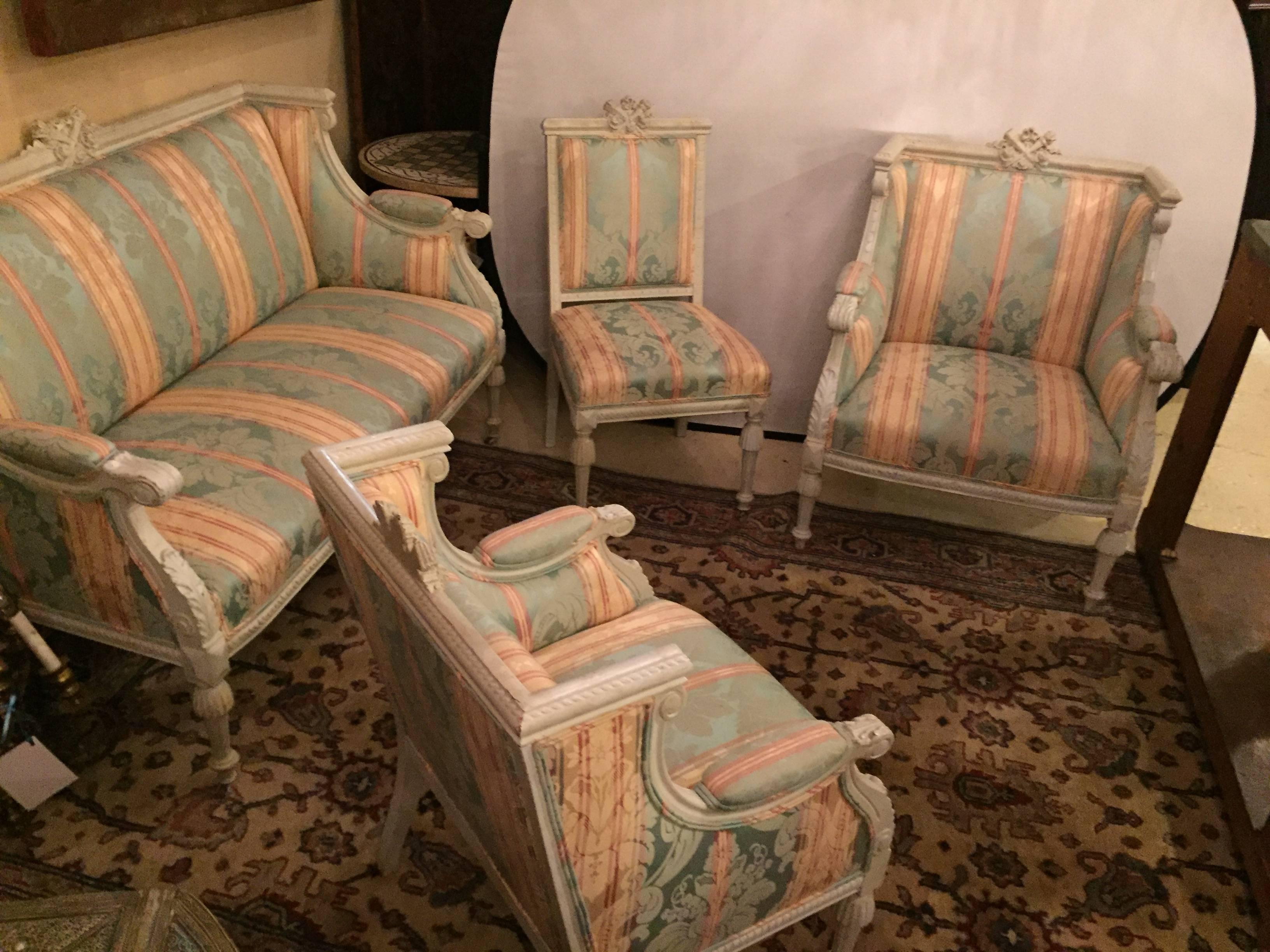 Swedish Fashioned Louis XVI style salon suite in off-white paint decorated finish. Consisting of a loveseat / settee and three different sized chairs. The whole in a nice clean stripped fabric covering distressed off-white finish frames. Each in the