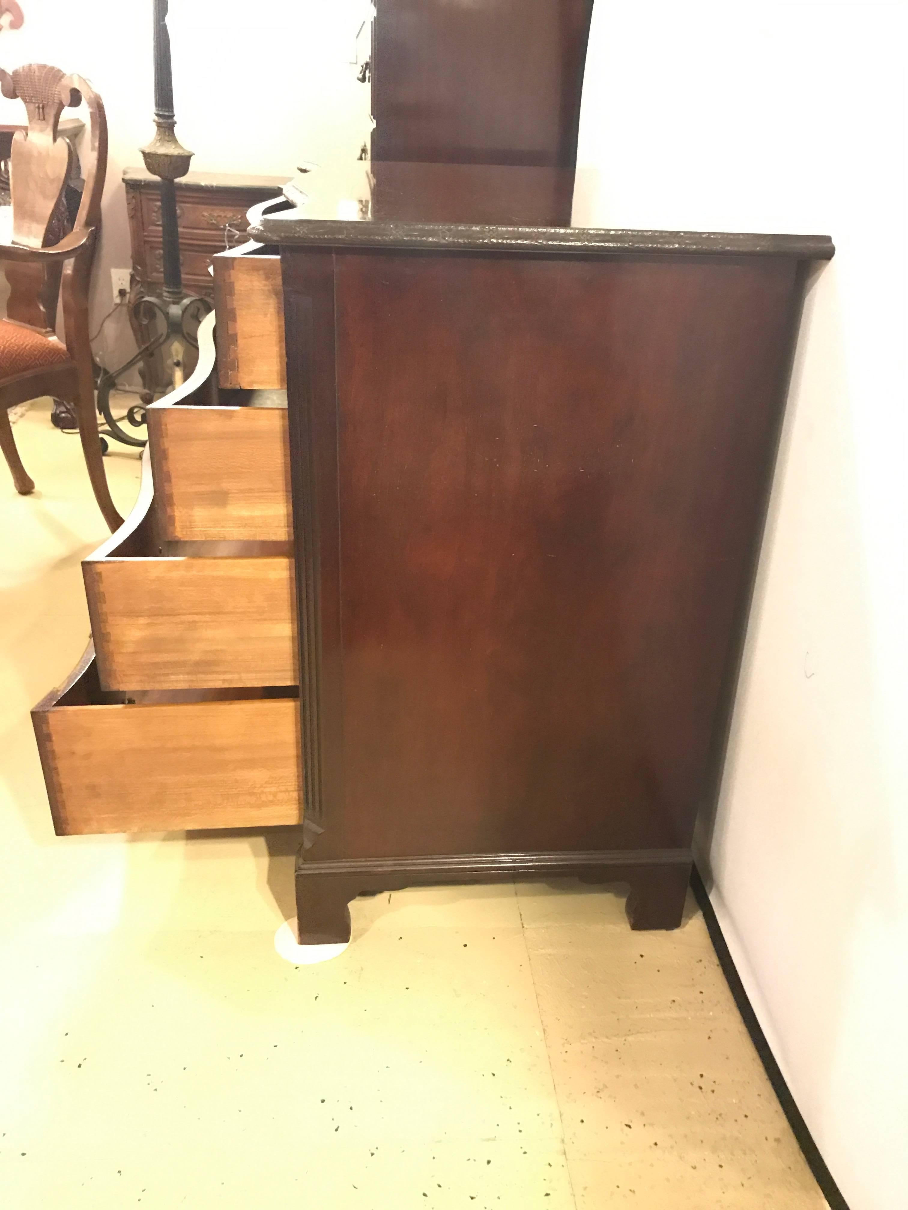 A flame mahogany four graduating drawer Georgian style chest or commode. Having four drawers on a flame mahogany case supporting a mahogany scalloped carved edge top all flanked by reeded column-form sides. This custom quality mahogany commode or