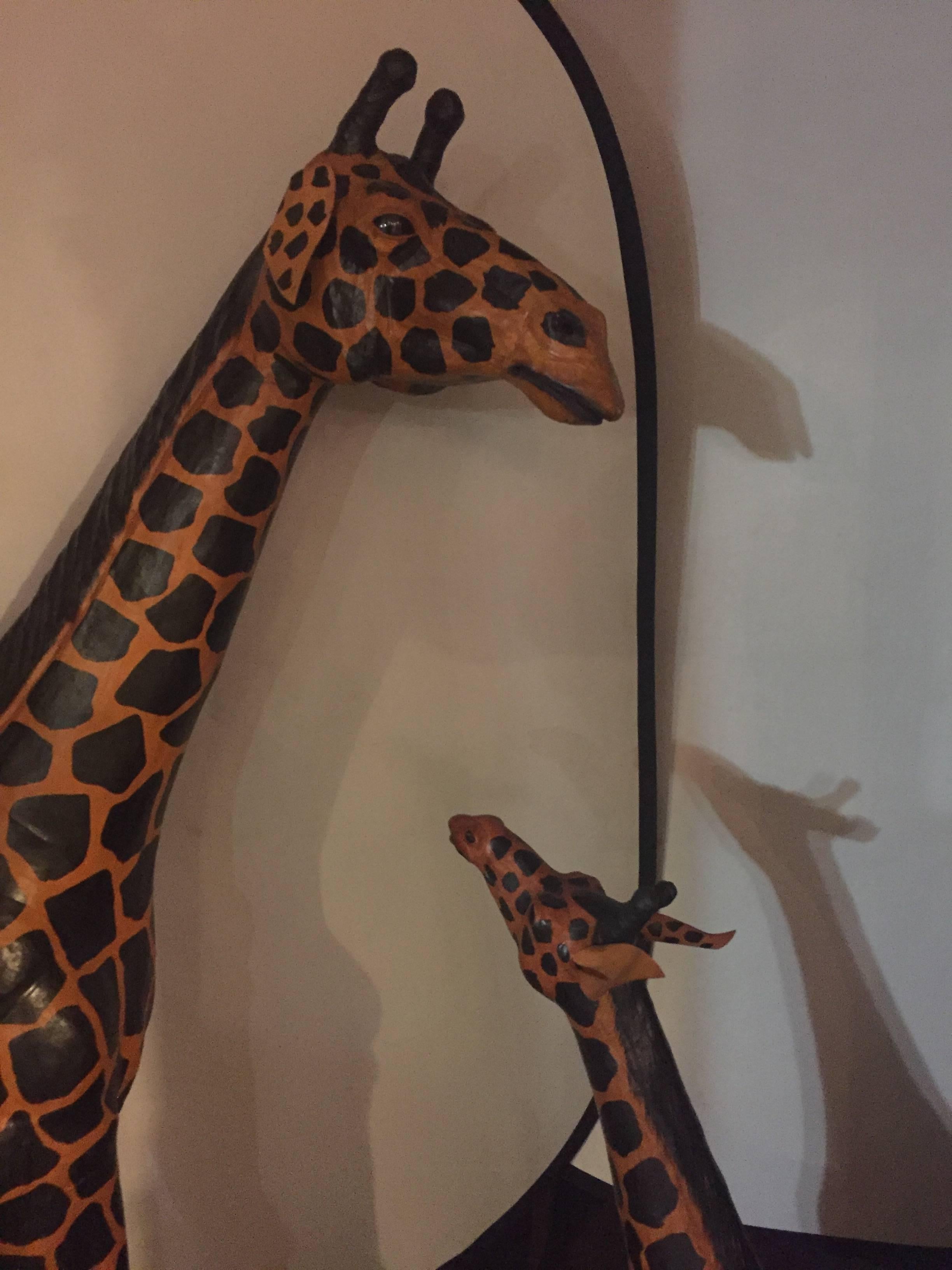 A pair of life-size giraffes each made of painted leather. This wonderfully lifelike monumental giraffes are sure to spark conversation in any room in the home or office. Can purchase one or the pair however, we would like to keep the family