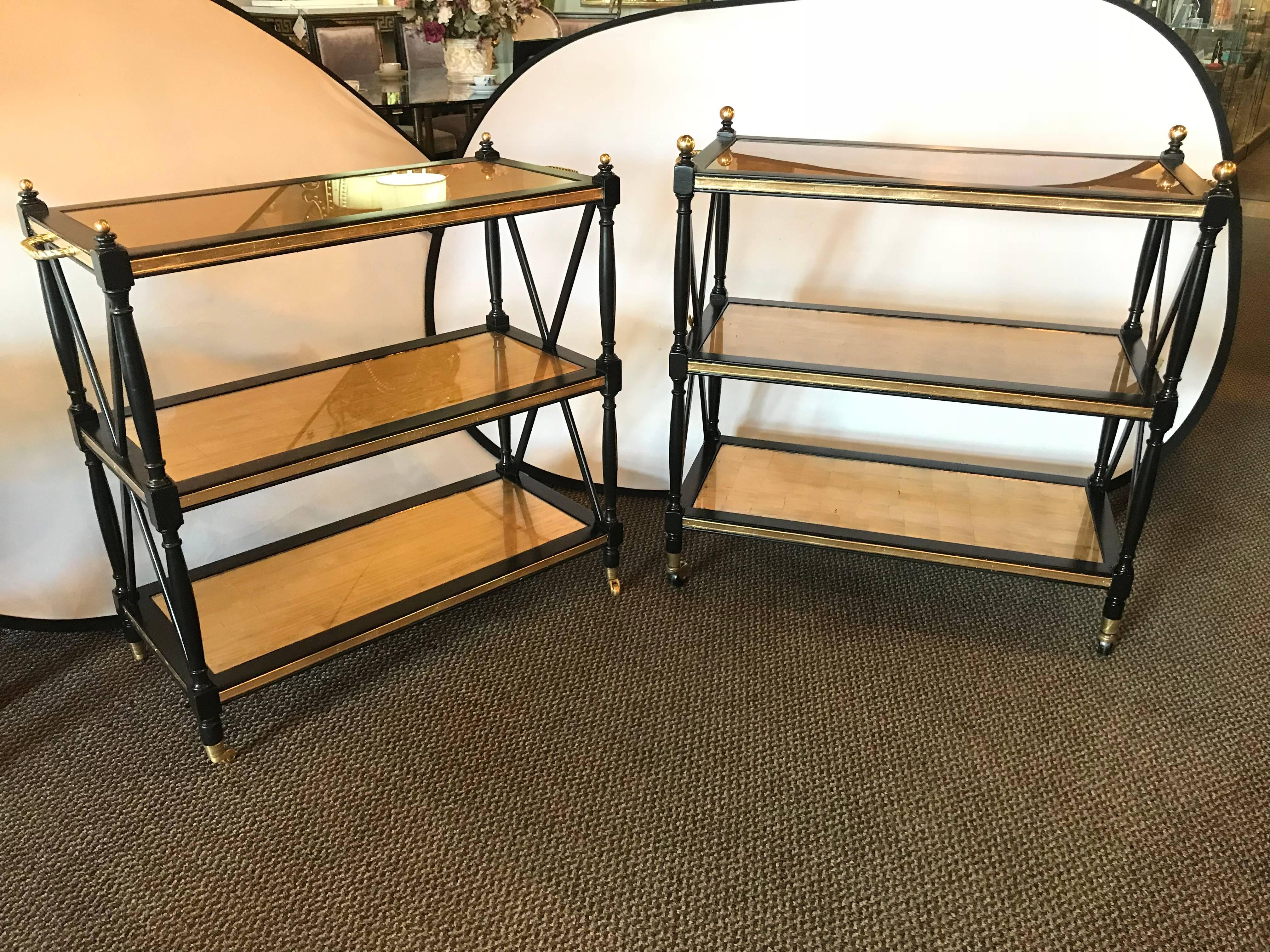 A Compatible  Pair of Fine Hollywood Regency Ebony and Gilt Glass Bronze Mounted Three-Tier Tea Serving Carts. Attributed to Maison Jansen. Each on casters having ribbed bronze framed aprons supporting the gilt glass shelves. One pair with slightly