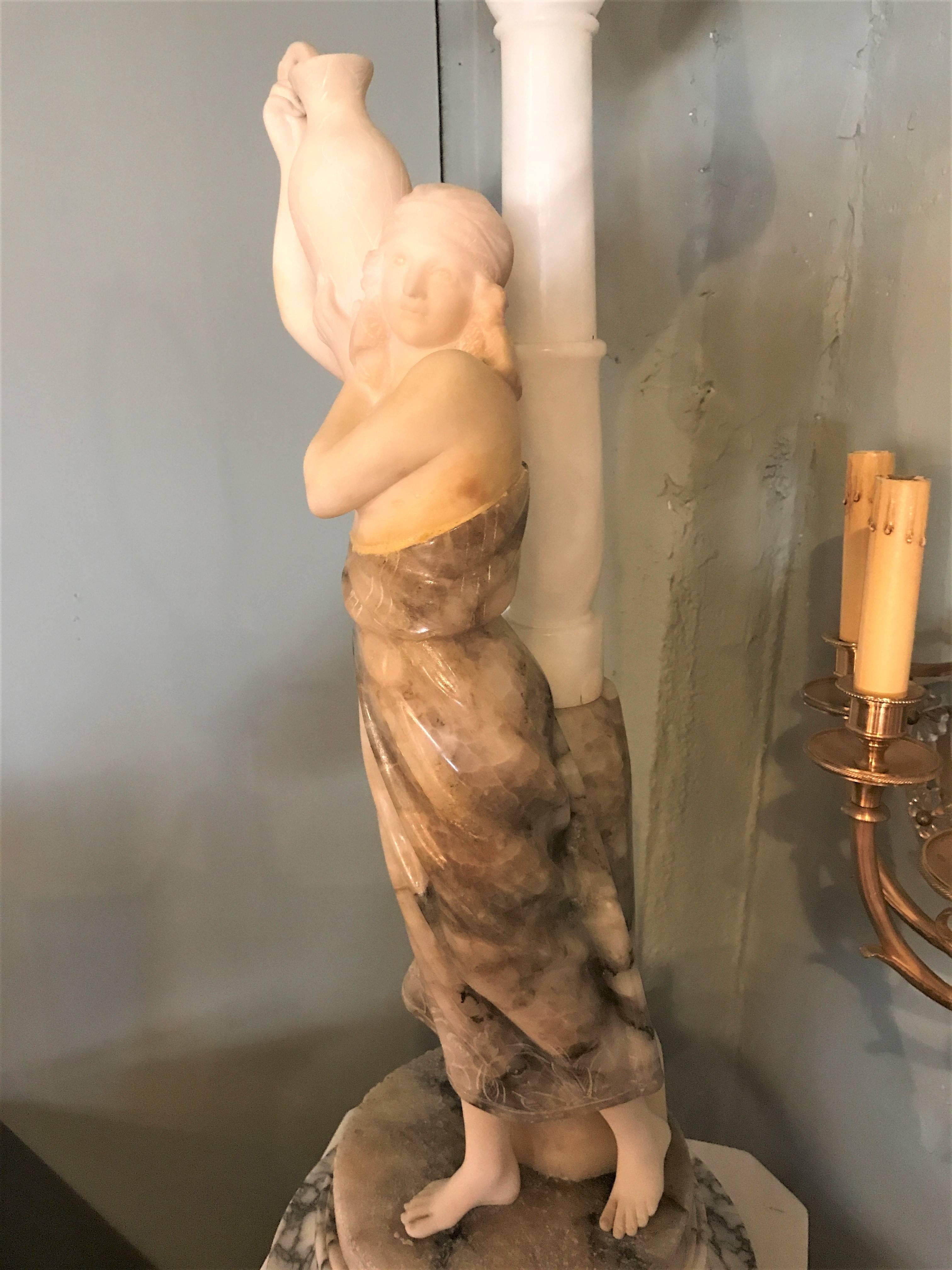 A fine alabaster figure of a water maiden on a pedestal. The single globe lamp is of a draped female water bearer with a lighted street pole behind her standing on a rock. The lamp figure on a tall alabaster pedestal.
 
72 inches high on pedestal. 