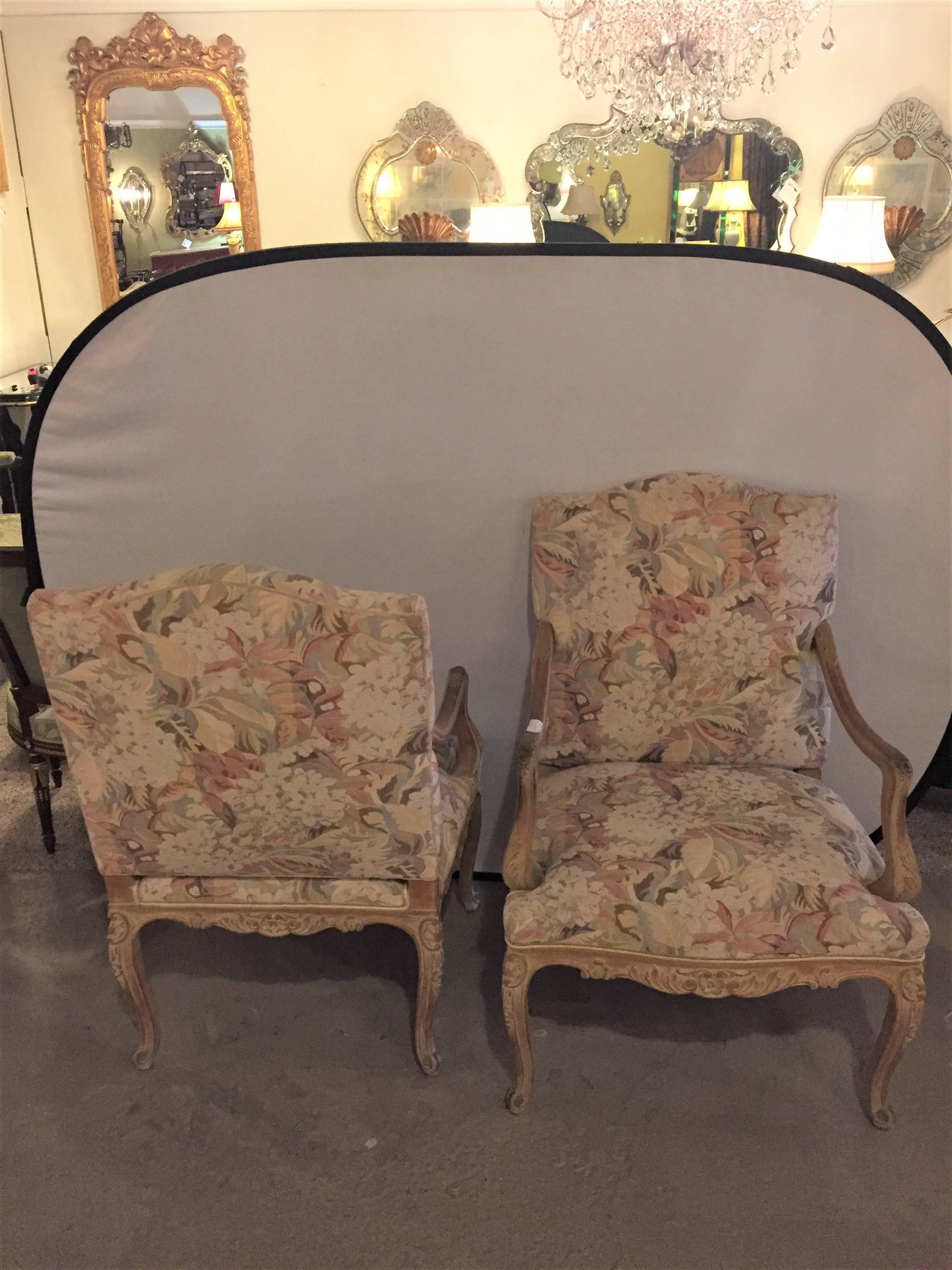 A pair of distressed finely carved Louis XV style fauteuils manner Jansen. The worn and distressed Louis XV style frames are wonderfully carved having flowing curved arms. Each in a fine upholstery.