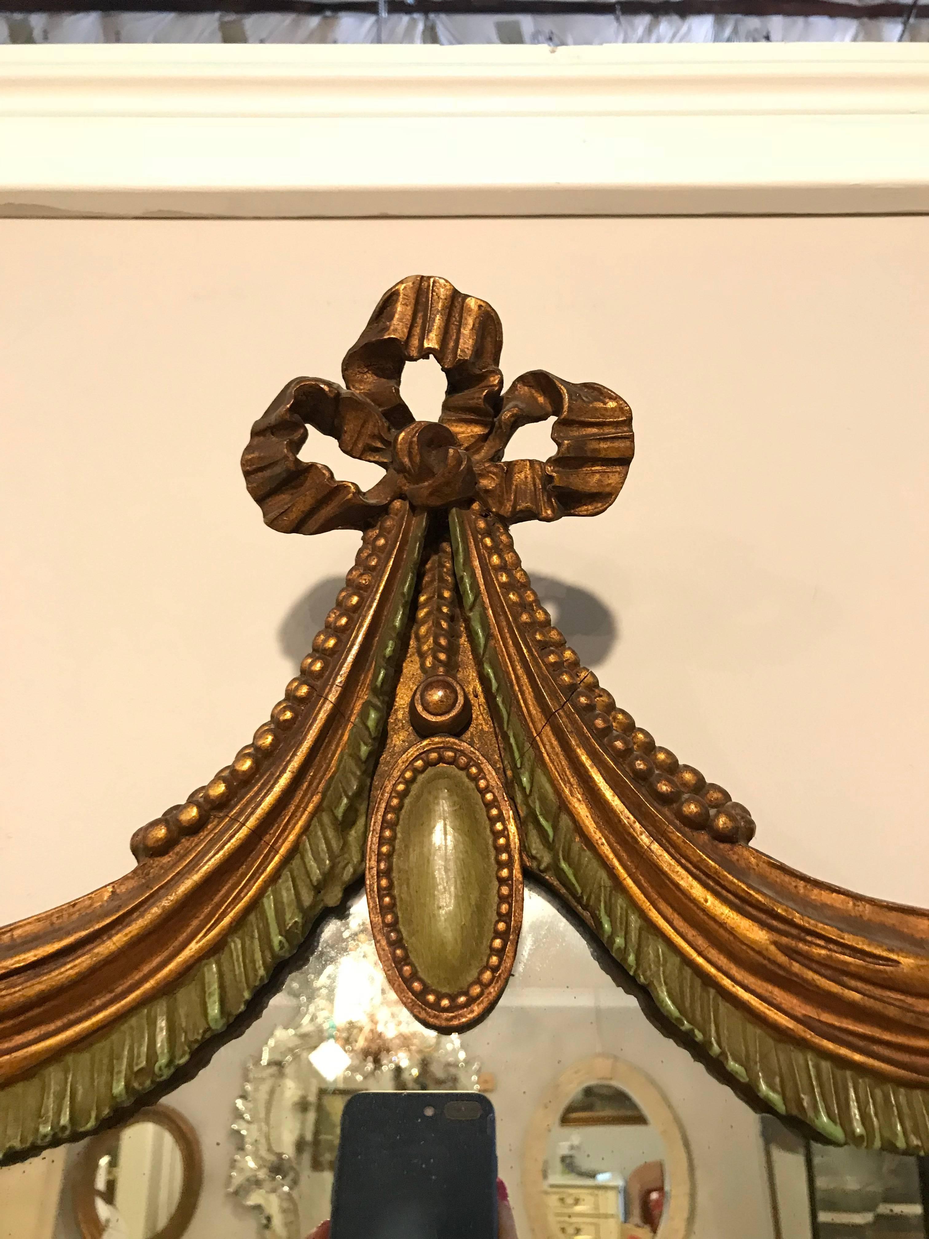This Hollywood Regency era Drapery and tassel form giltwood wall or console mirror style of Dorothy Draper. This gilt wooden and green paint decorated wall or console mirror is simply stunning and leaves not detailed left to the imagination. This