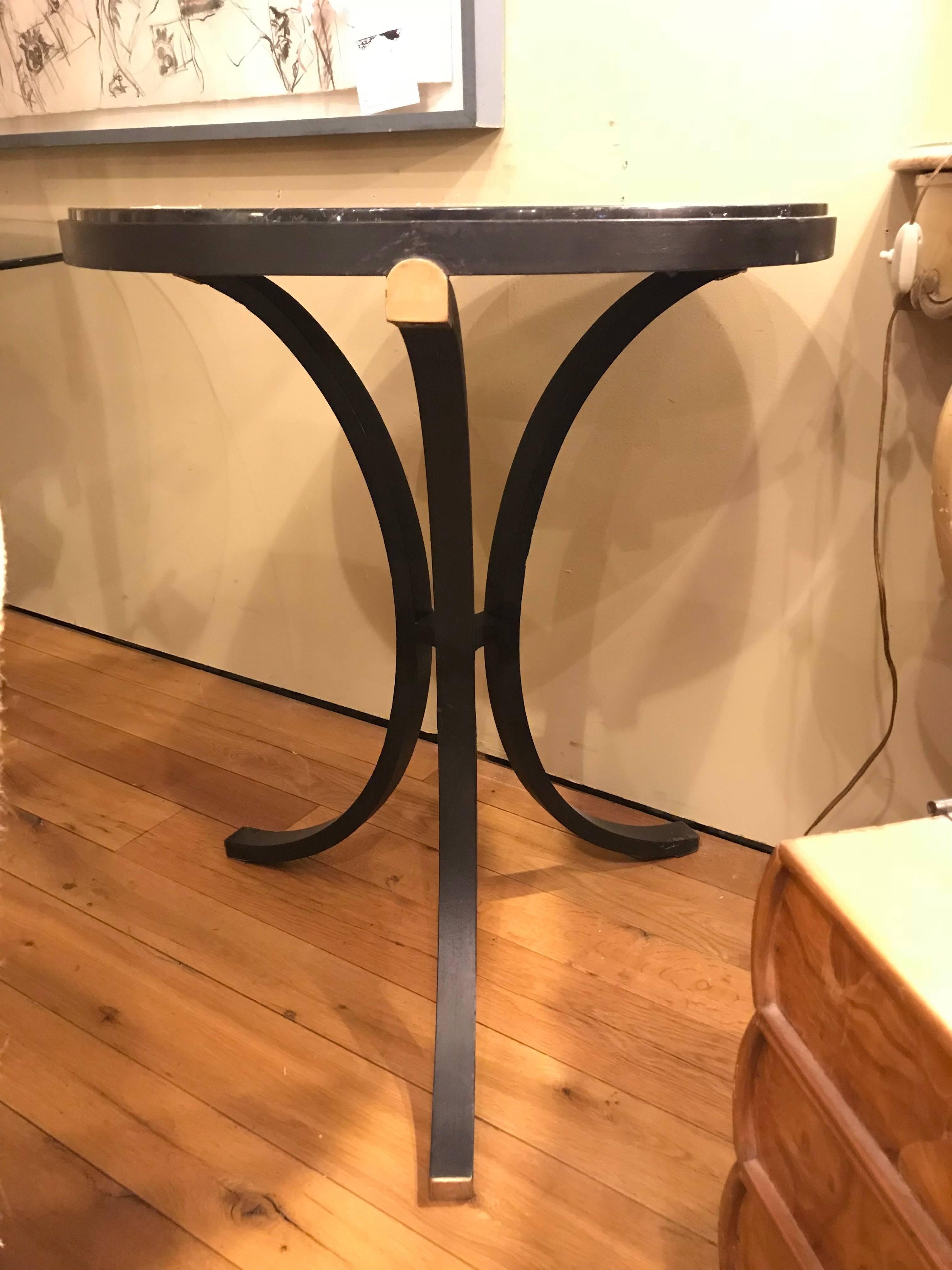 Hollywood Regency style pair of marble top iron base circular stands end tables. Each having an almost mirror like marble top with an ebony base sporting gilt hi lights.