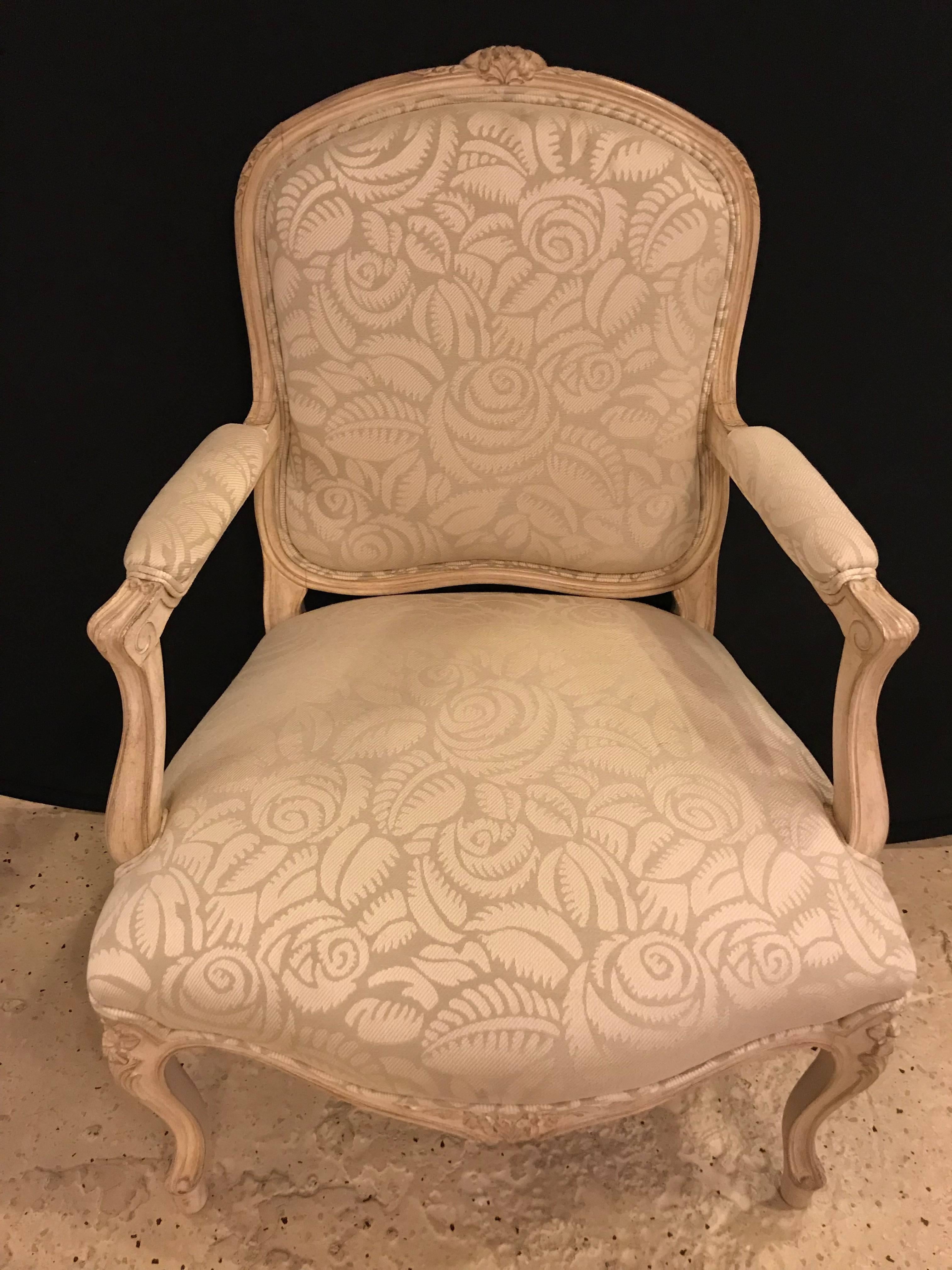 Paire de fauteuils bergère de style Louis XV. Chacun a un cadre finement sculpté et un tissu à motif floral net avec des rosettes sculptées tout au long.