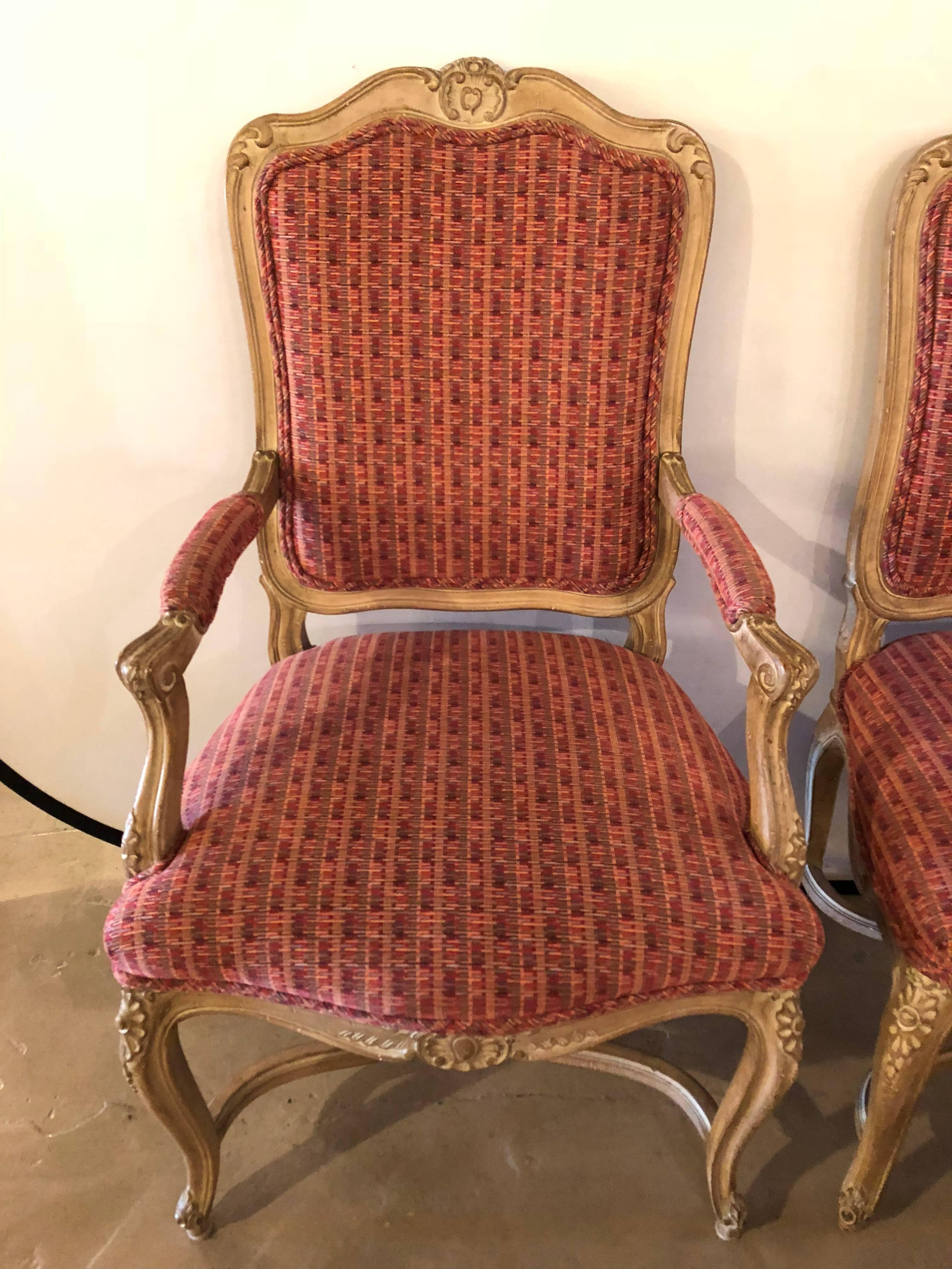 Set of six side and two armchairs. These fine carved dining chairs by Maison Jansen in the Louis XV style are finely carved and detailed. Each in a Weathered finish having a burgandy and gray fabric. Each with a X-form undercarriage. 

This set is
