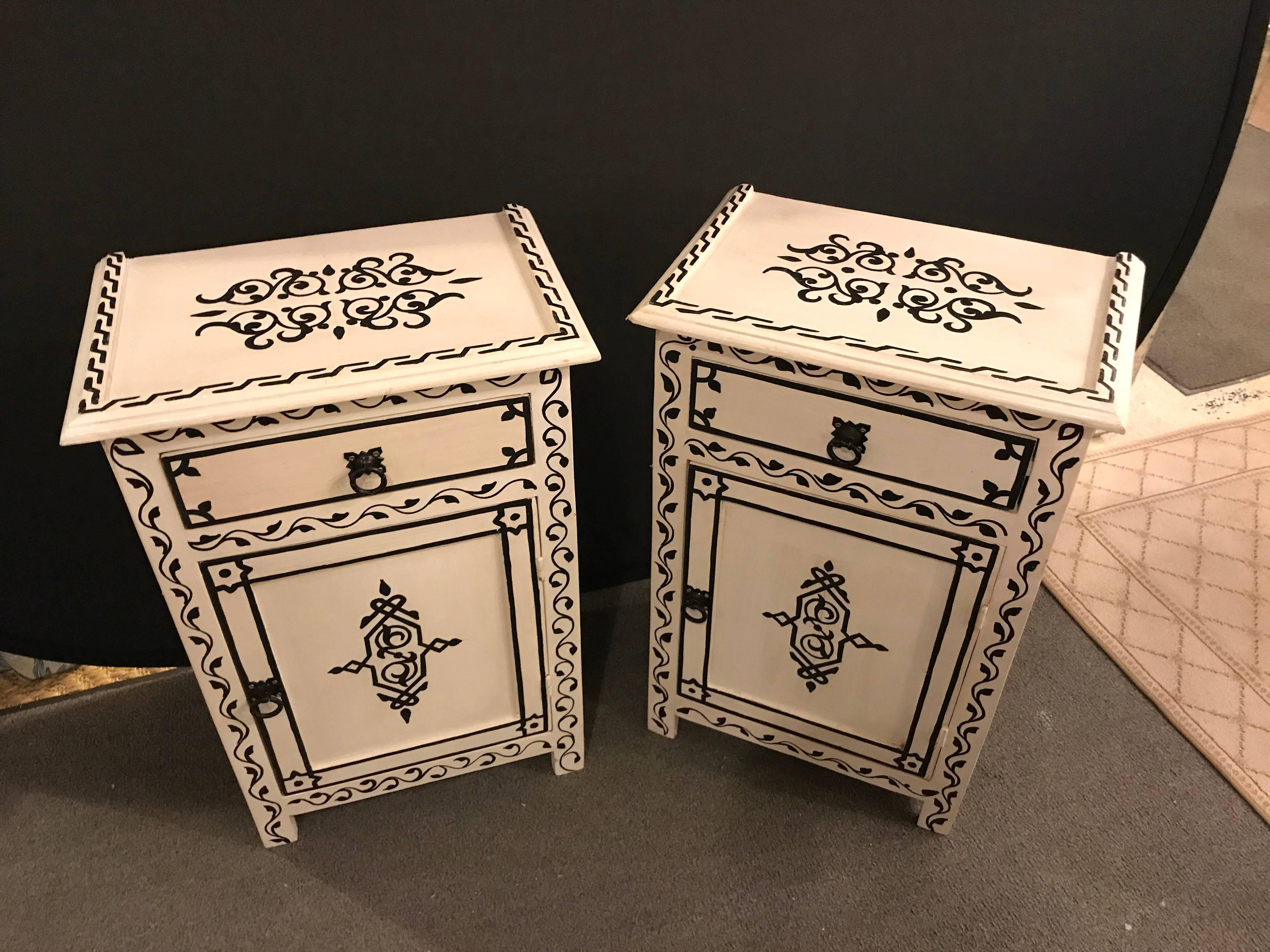 A pair of hand-painted Moroccan nightstands or end tables. Hand-painted by master artisans, this stunning pair of Moroccan nightstands features lattice work and impresses with its unique design and a welcoming black and white color.
 