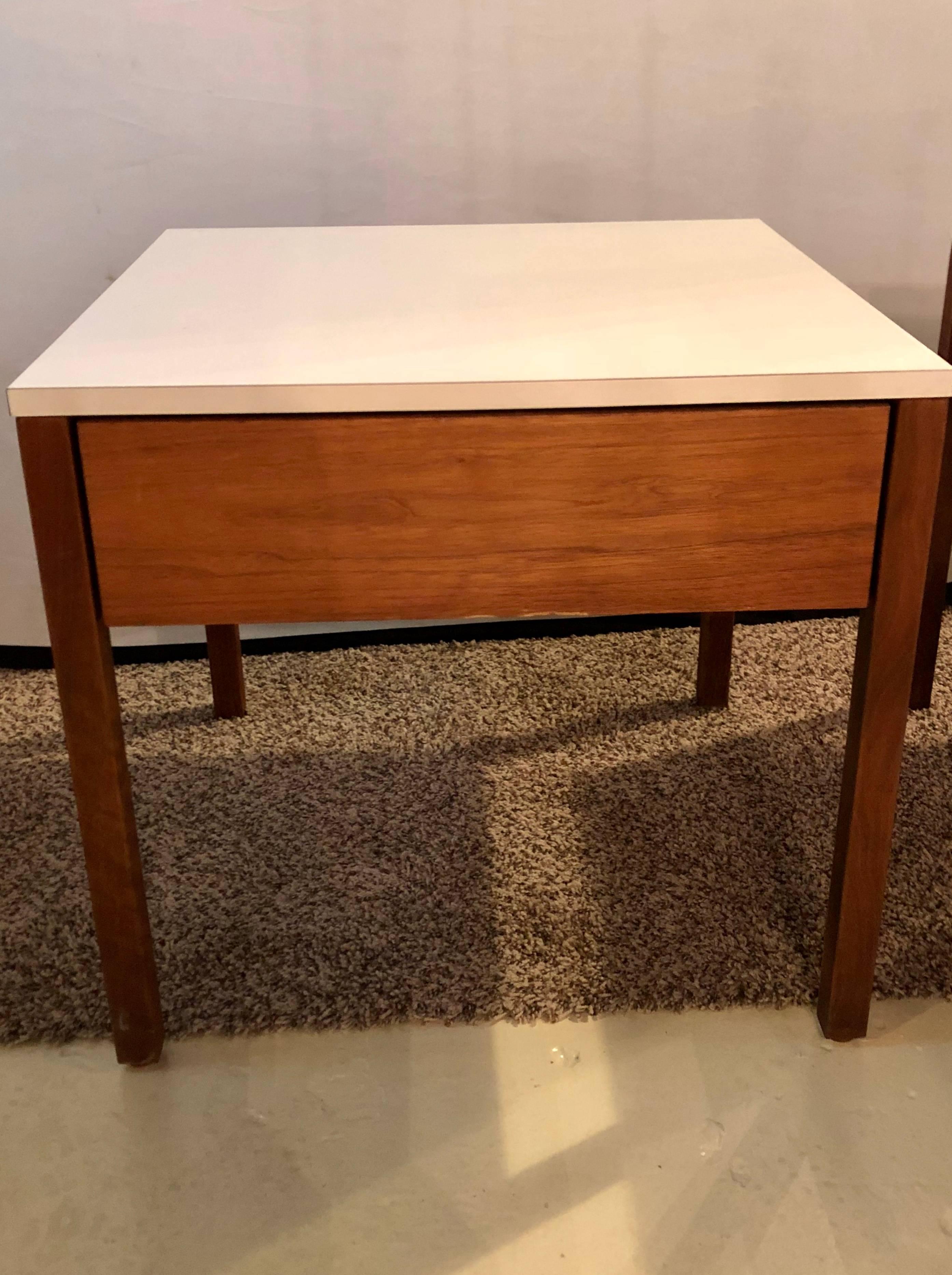 A pair of Mid-Century Modern signed Florence Knoll nightstands or end tables. Each of these fine custom quality walnut chrome stands have a single drawer under a white laminate top. Both are labeled on the underside. This fine pair have a matching