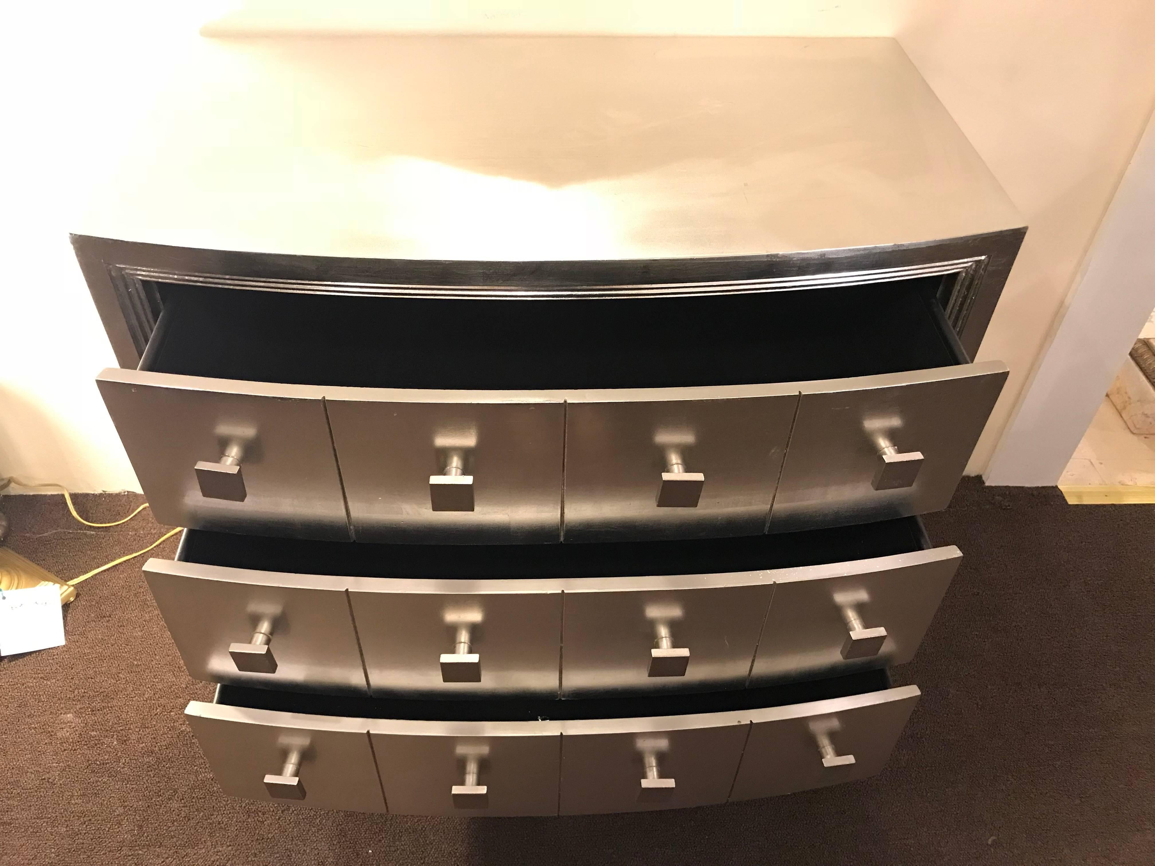 A pair of custom three drawers demilune chests or nightstands or commodes. Each of silver leaf form with square drawer pulls.