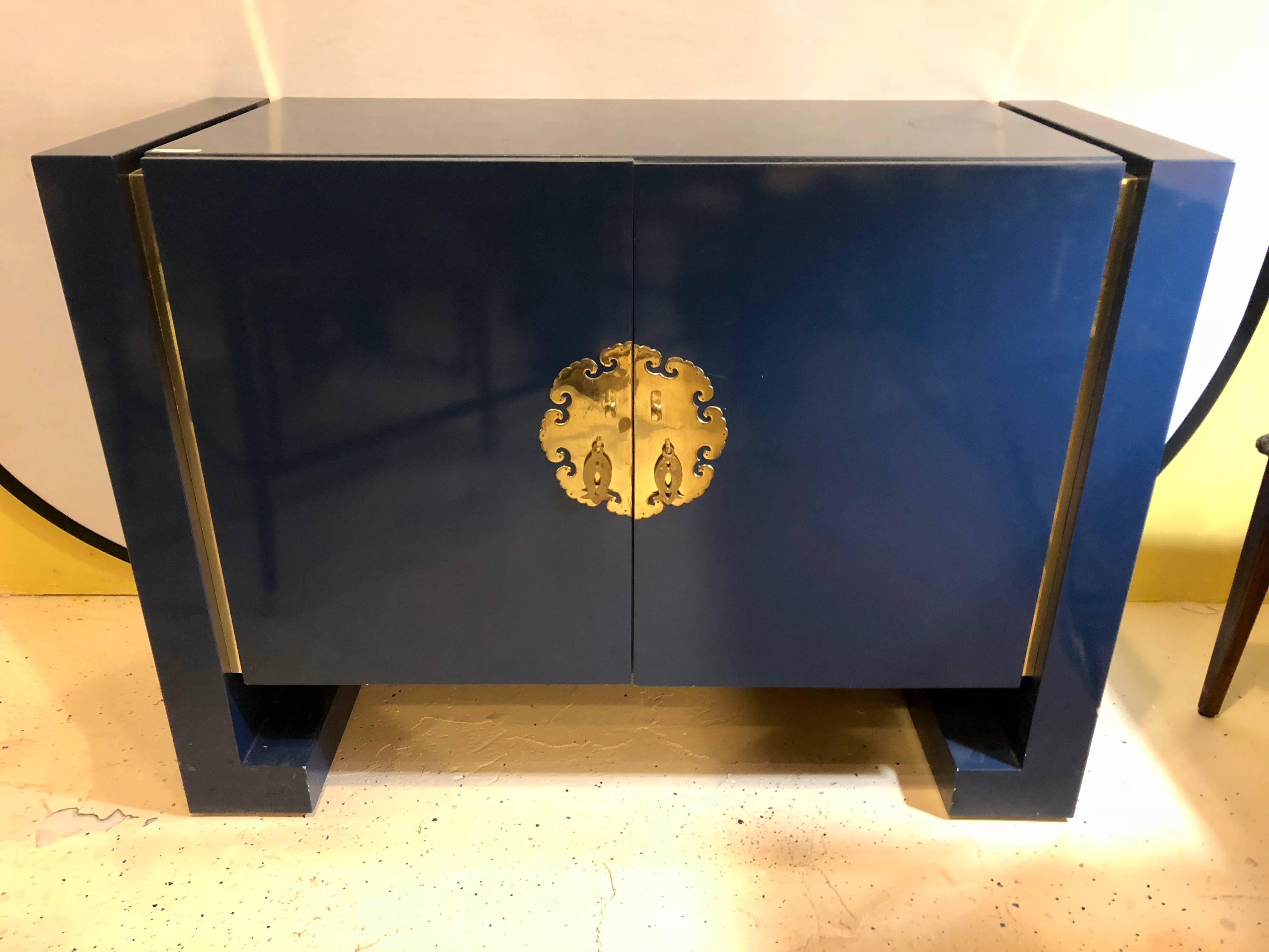Blue designer oriental cabinet in the style of James Mont. This cabinet certainly custom quality made for one with a desired taste for quality has full bodied fish pulls on brass back grounds leading to an interior shelved cabinet. The exterior of a