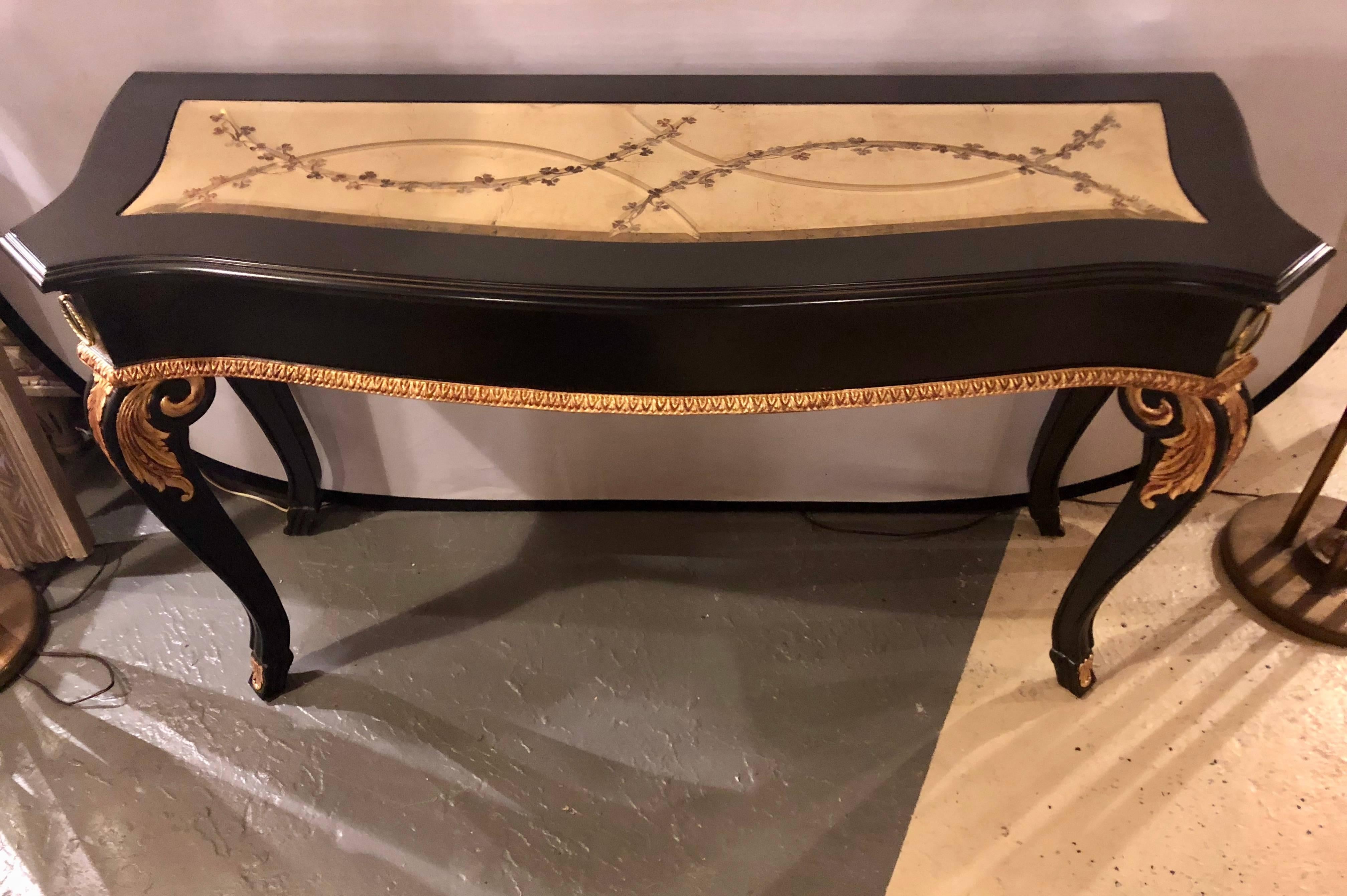An ebony and parcel-gilt decorated console or sofa table with fine beveled gilt glass top in the Hollywood Regency fashion.