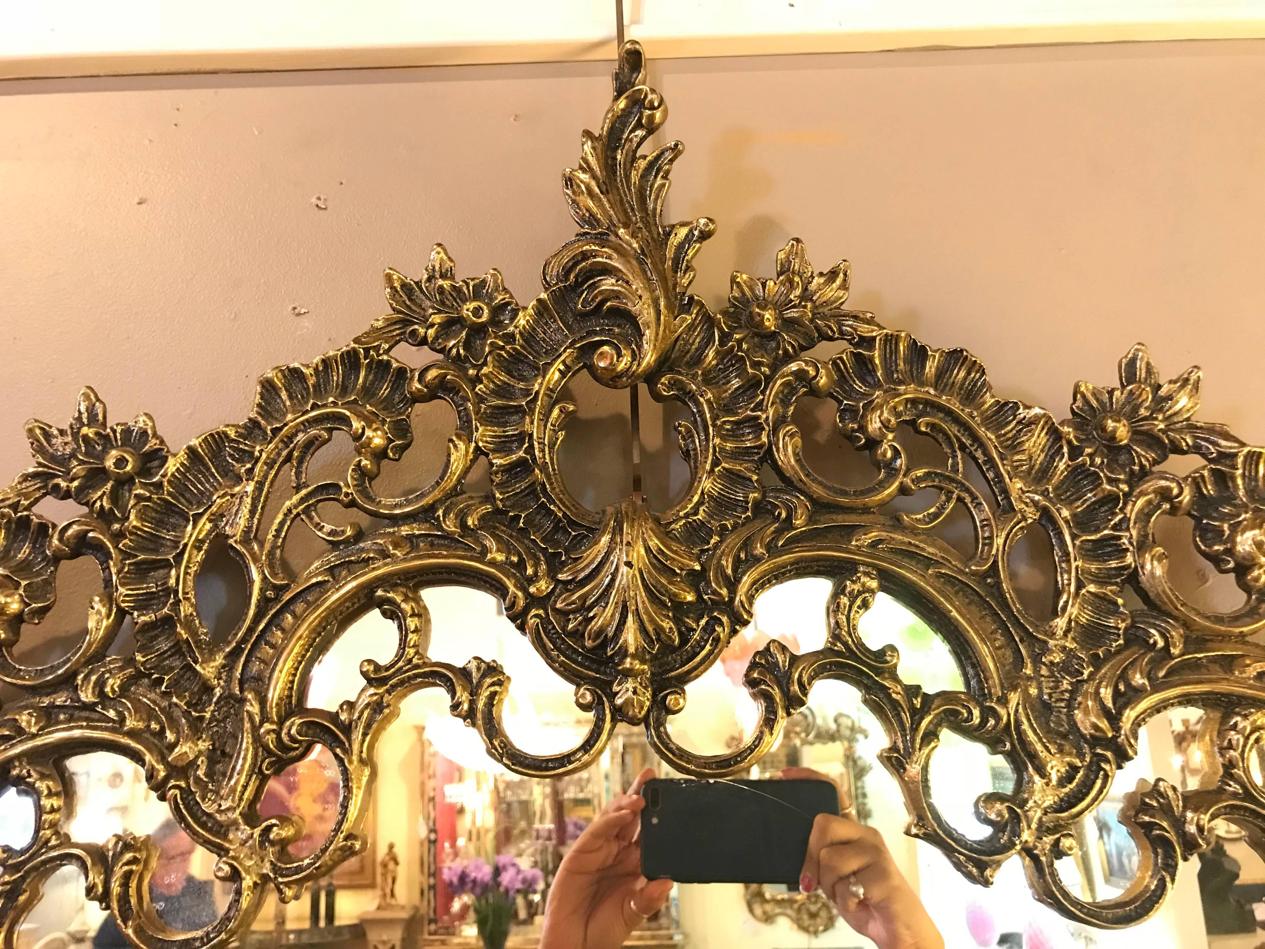 A pair of ornate Rococo style solid brass console or pier mirrors. These one of a kind mirrors are simply spectacular and are certain to demand attention in any room in the home or office. With intricate and pierced carved frames the center clean