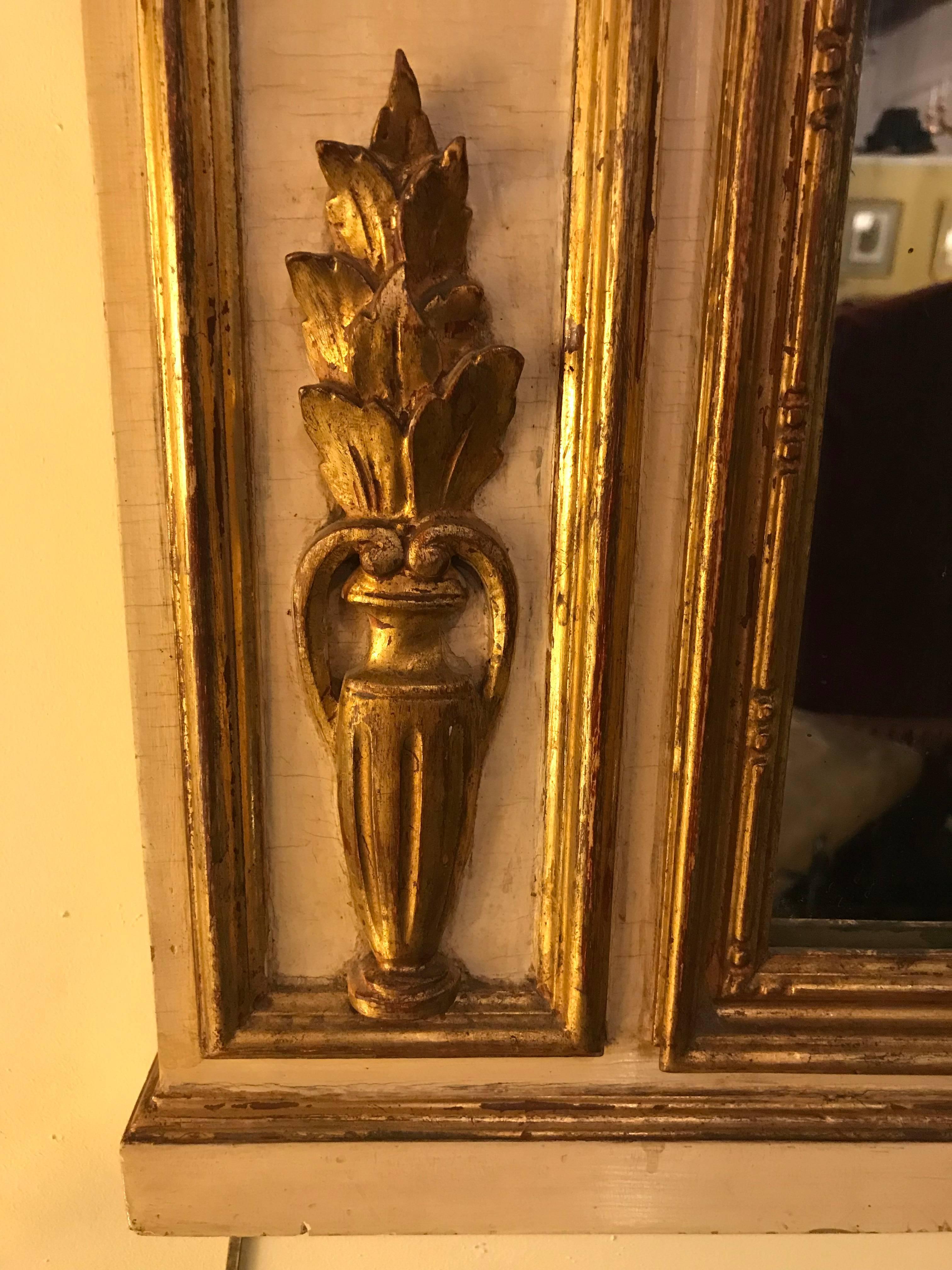 Französischer bemalter und paketvergoldeter Trumeau-Spiegel im Louis-XVI-Stil. Dieser wunderschön geschnitzte Spiegel kann als Wand-, Konsolen- oder Kaminsims-Spiegel verwendet werden. Die zentrale Szene eines Horns in Quaste mit geschnitztem Band