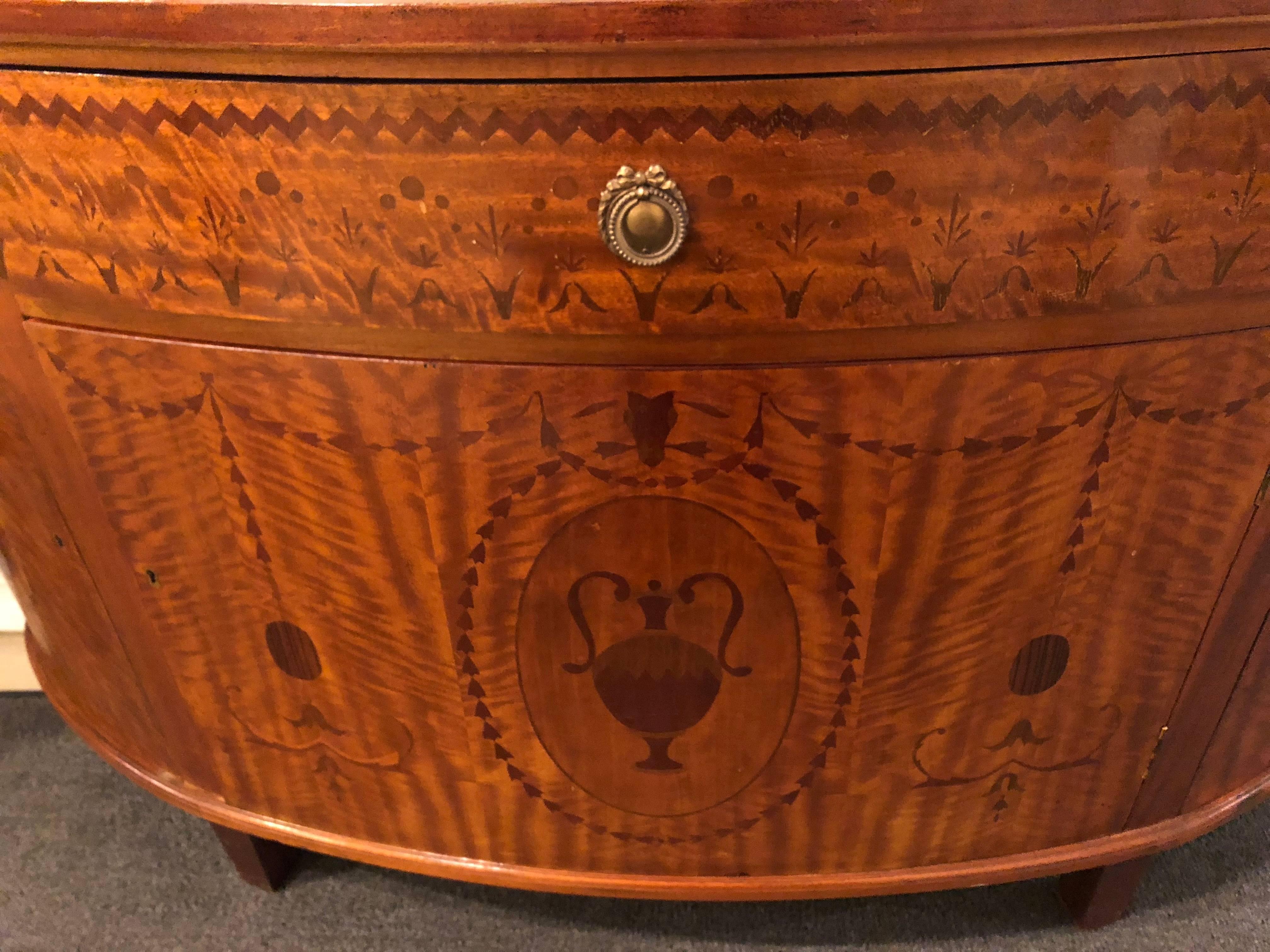 Pair of Palatial Adams style demilune consoles cabinets or commodes. Each with a fine inlaid demilune top above a large centre door leading to a shelved interior flanked by inlaid demilune sides having doors leading to shelved interiors as well.