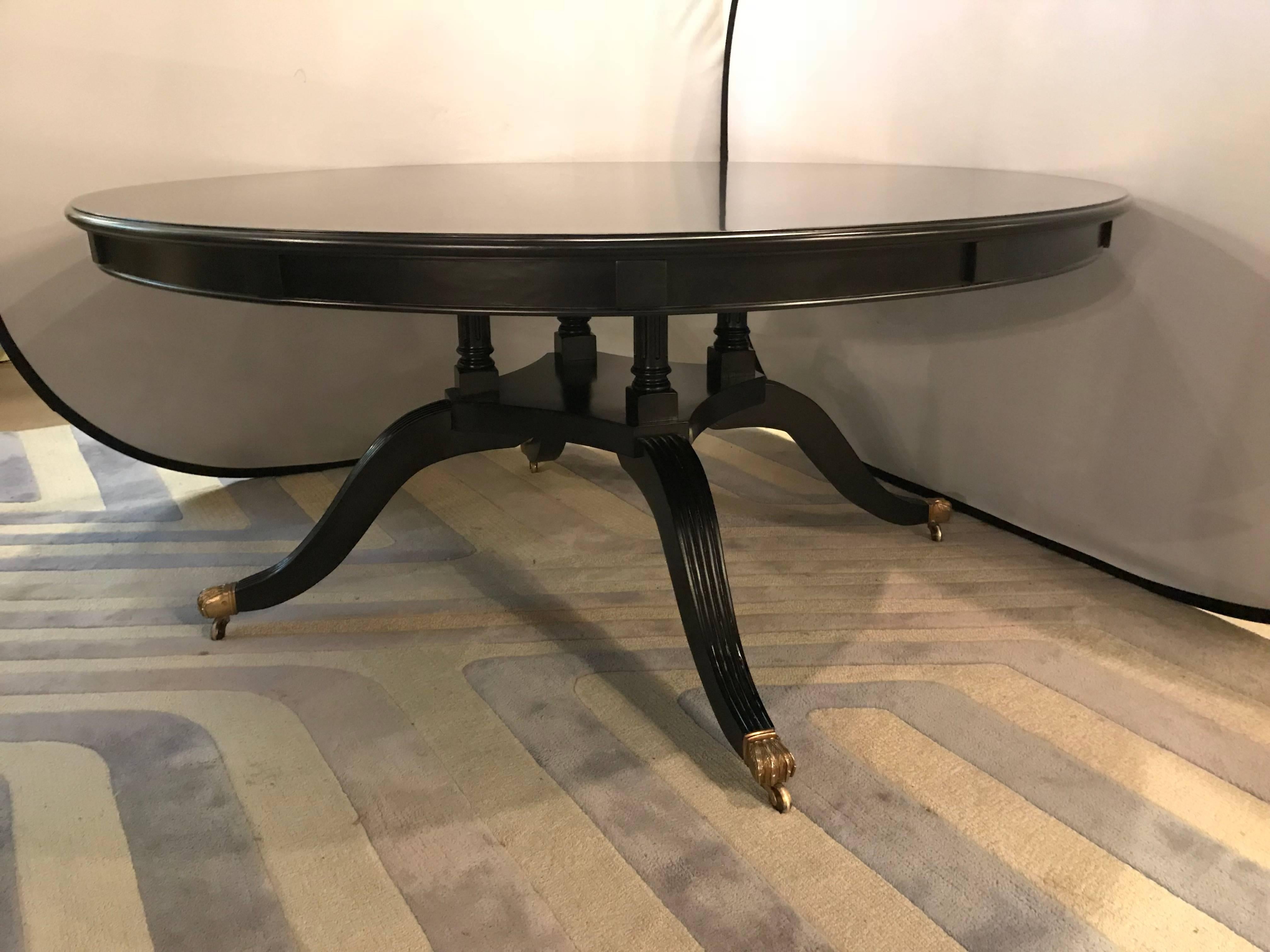 Monumental Hollywood Regency Style custom-made ebony circular extending dining table. This finely crafted one of a kind dining table comes with six twelve inch leaves which extends the 65 inch circular dining table into a palatial eighty-nine inches