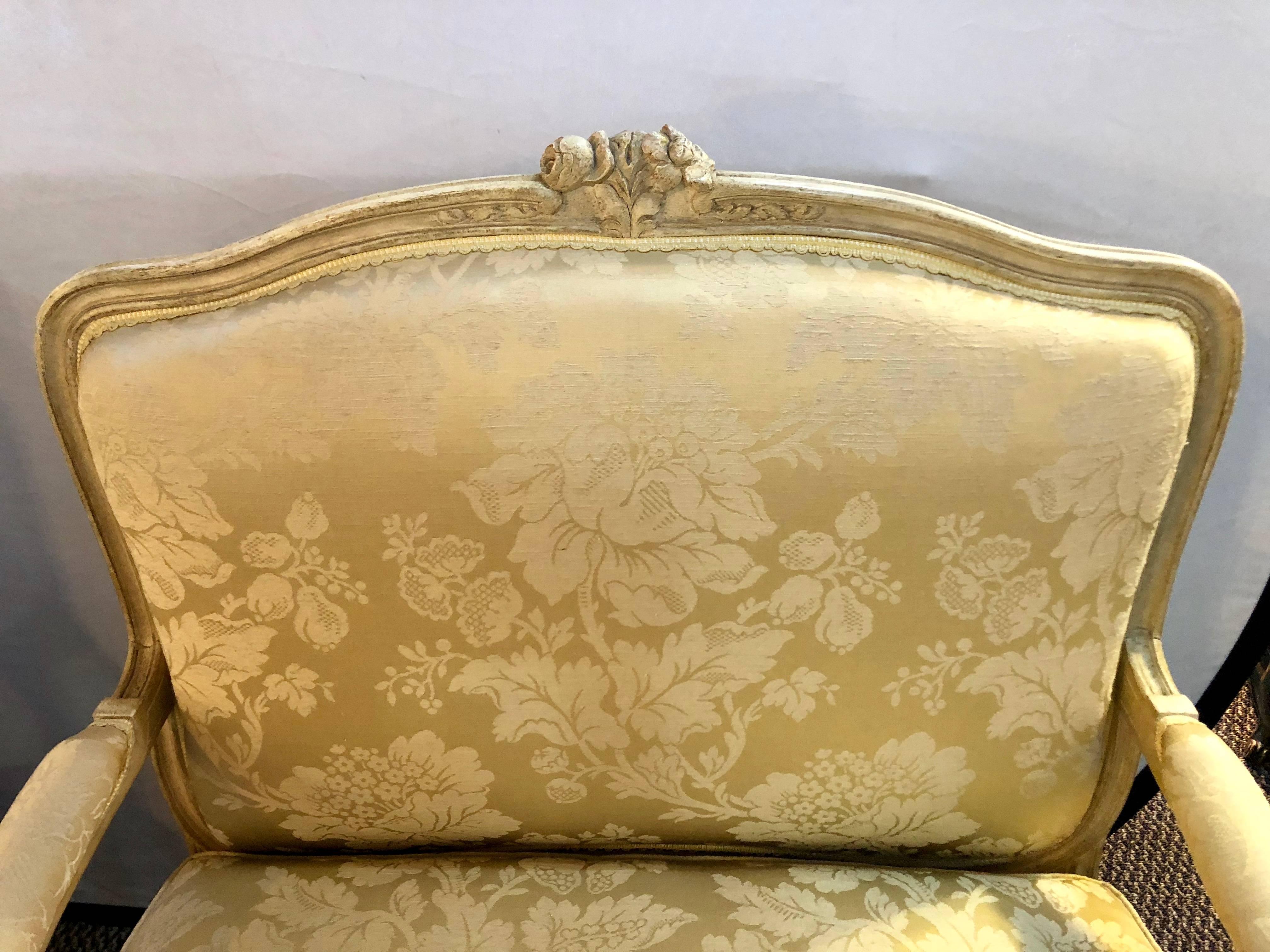 Une paire de chaises longues de style Louis XV par la Maison Jansen dans leur tissu d'origine. Une paire de chaises finement sculptées avec une finition vieillie et des bras latéraux ouverts. Chacun d'eux est fabriqué dans un tissu floral épuré avec