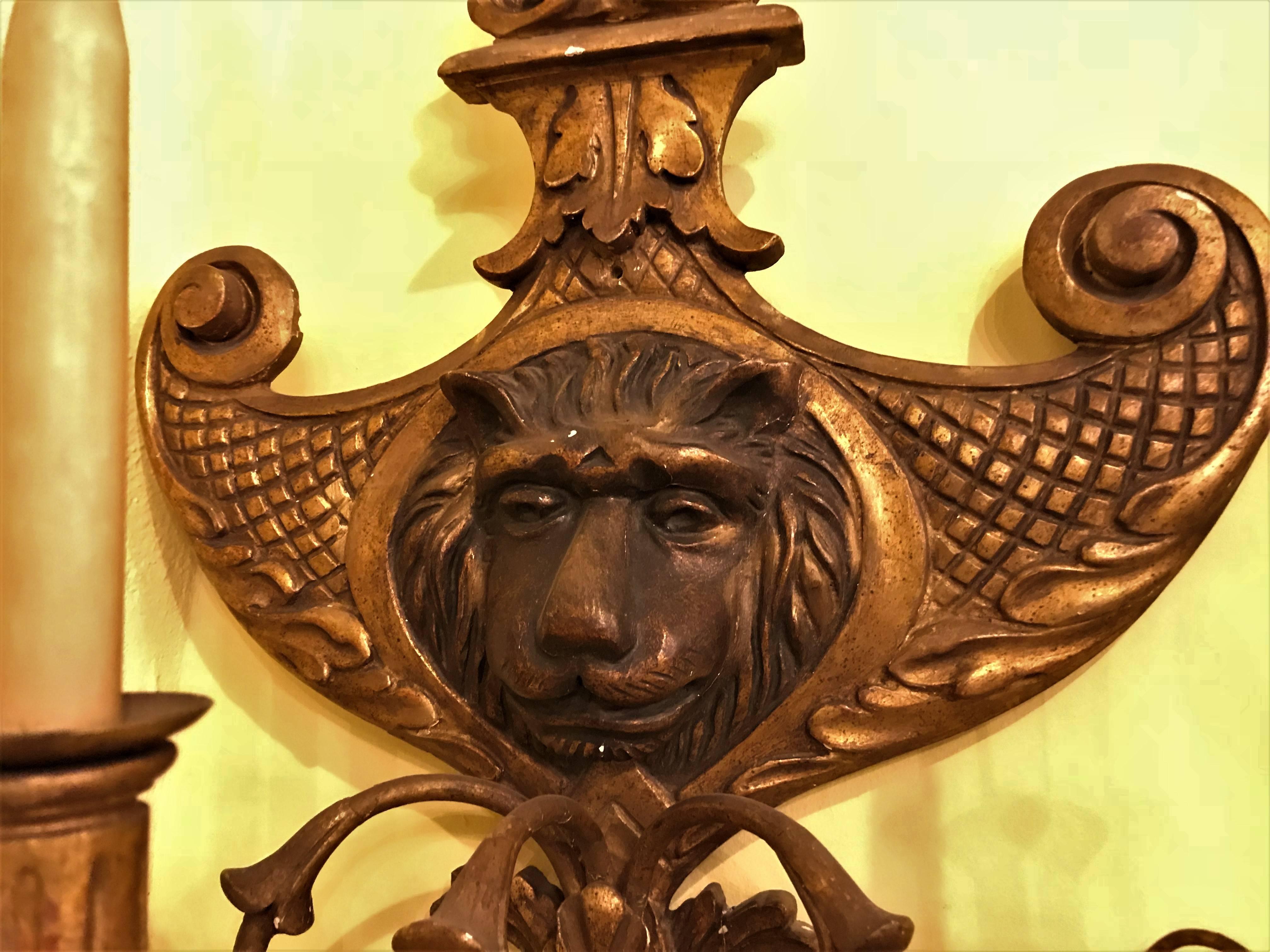 A 19th century pair of carved lion head shell form wooden sconces. The central lion head with full mane flanked by a giltwood carved three arm wall sconce with hanging crystals.