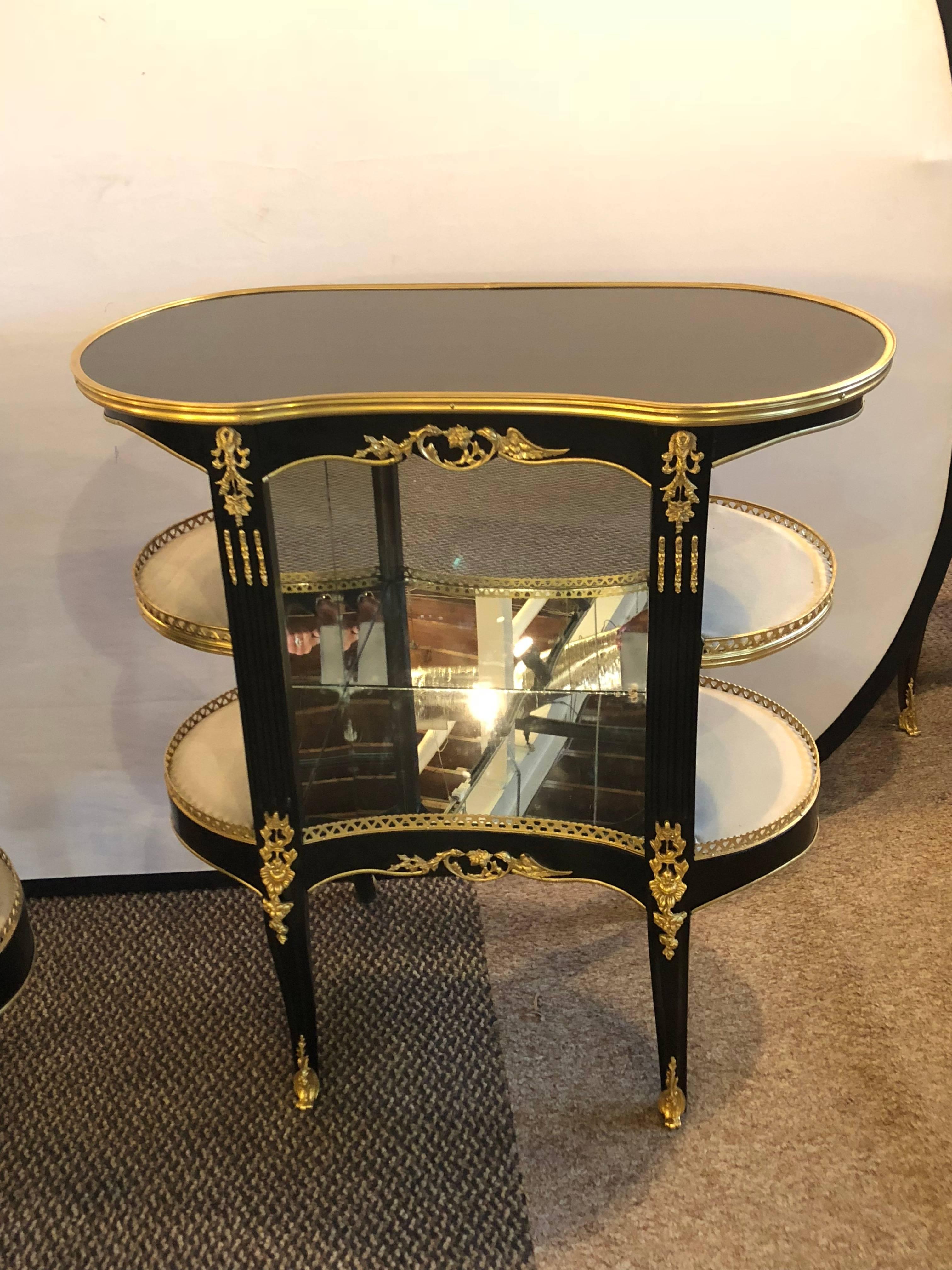 A very fine and decorative pair of Louis XV Hollywood Regency style ebony Vitrine form end tables or nightstands. These custom quality nightstands can be used as end tables or showcase pieces in a vestibule. The bonze mounts are wonderfully cast in