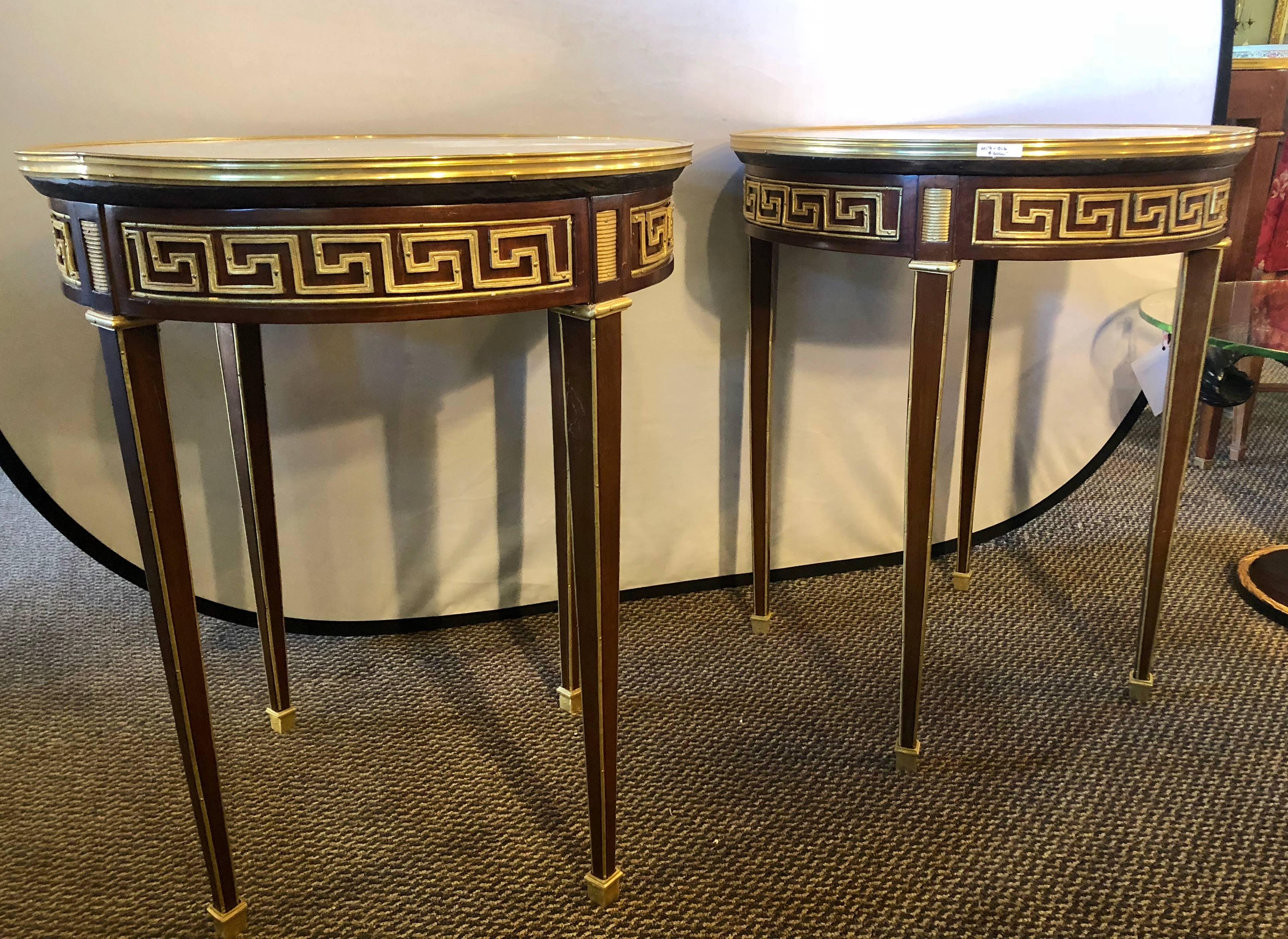 Pair of Greek key designed bronze galleried marble top mahogany Bouillotte or pedestal tables. These are simply the most stunning pair of Hollywood Regency style end tables or pedestals on the market. The tapering legs having bronze sabots with